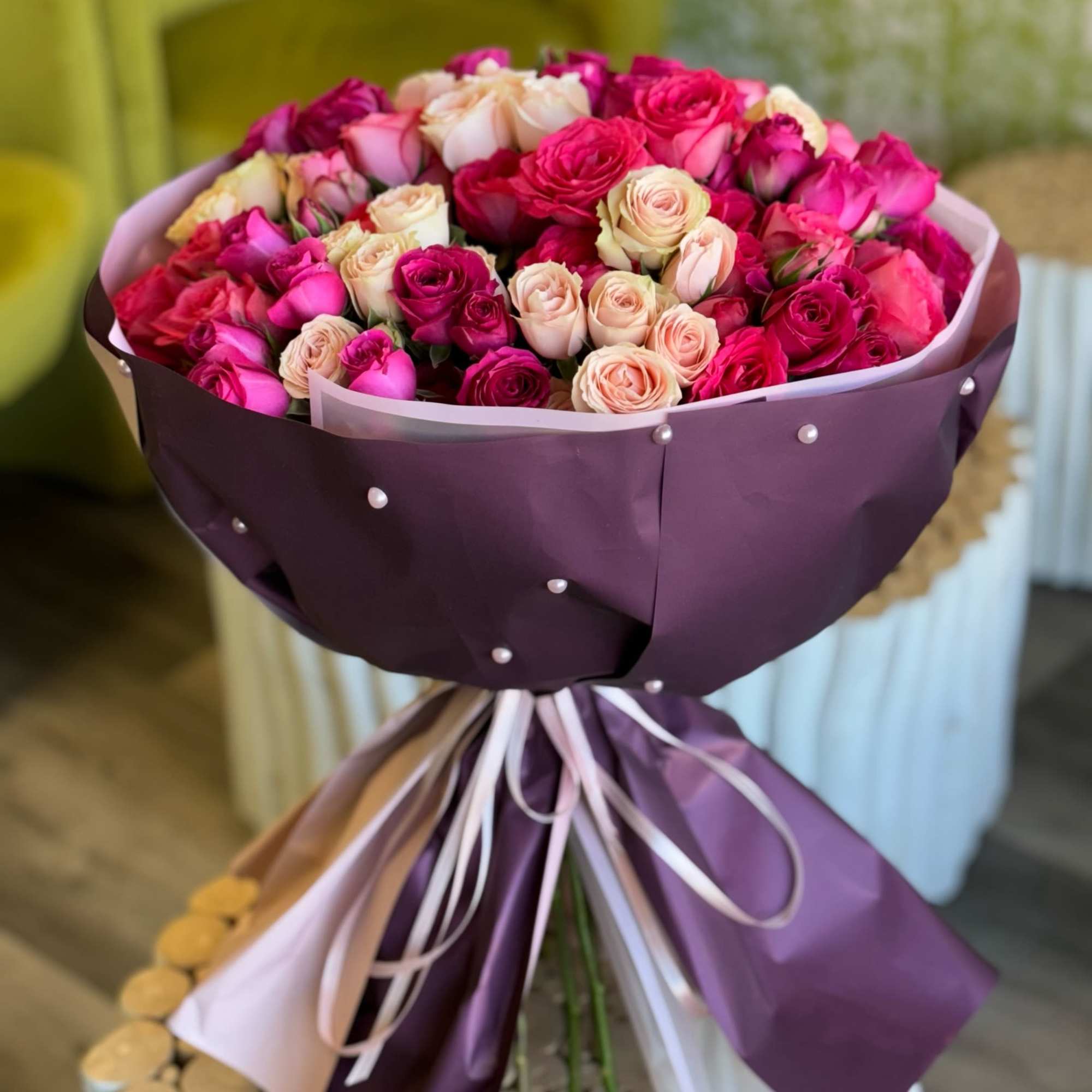 Bouquet of pink and cream roses wrapped in purple paper