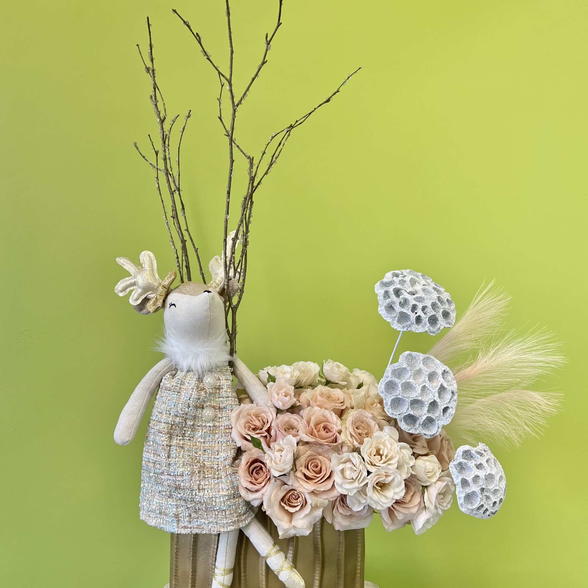 Floral arrangement with blush roses and a decorative bunny figure in a gold vase