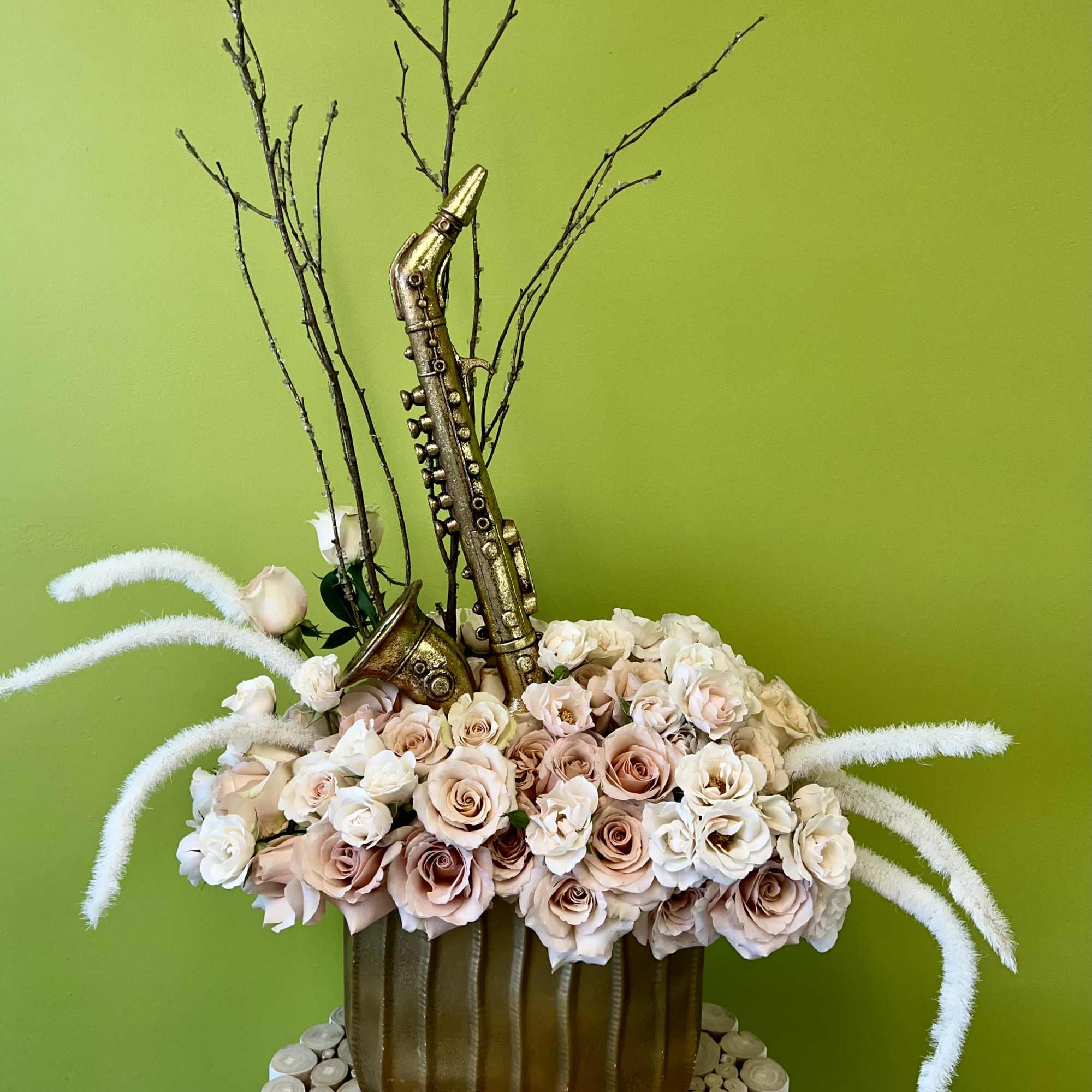 Arrangement of pale roses with a gold saxophone decoration in a brown vase