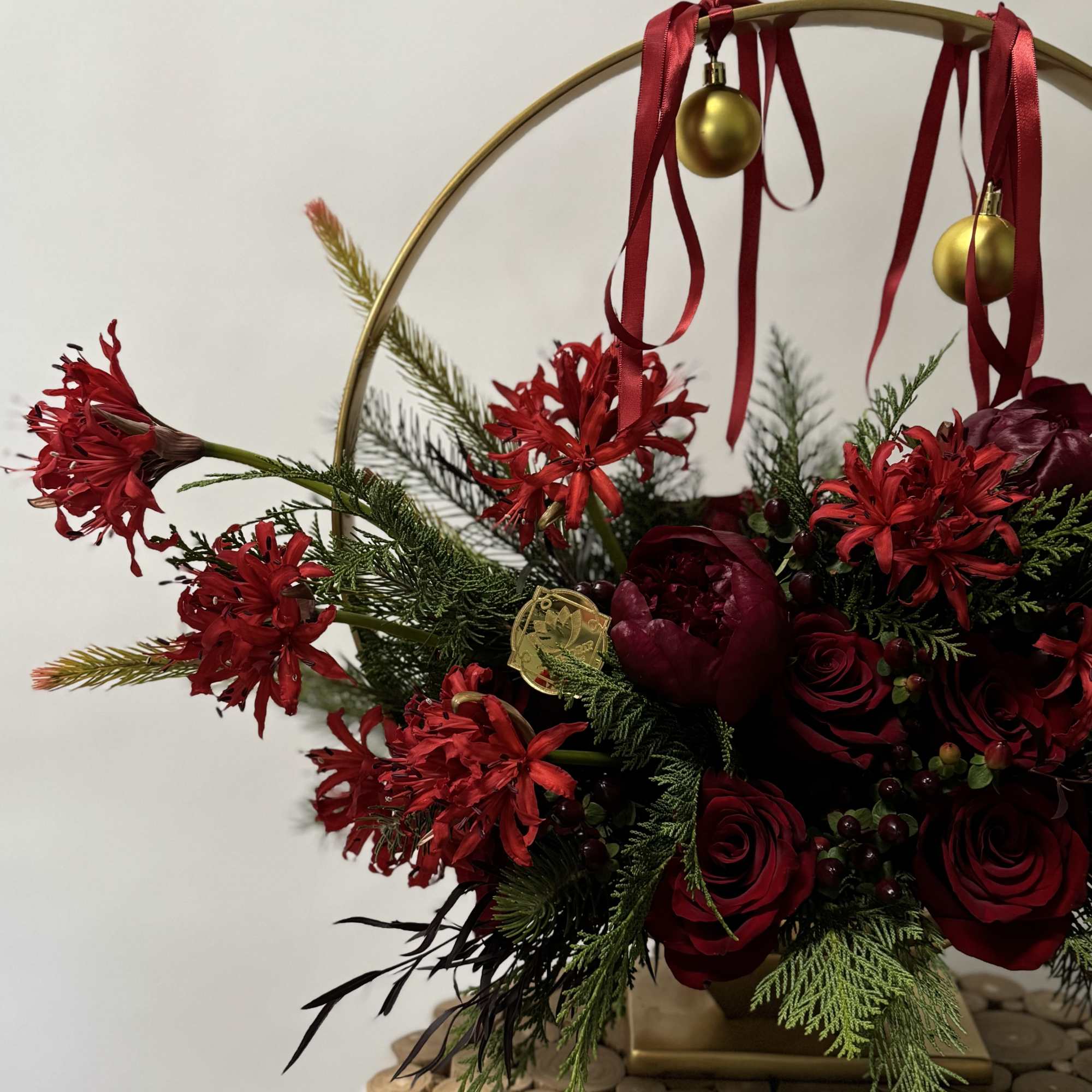 Red floral arrangement in a gold hoop with ribbon and ornaments