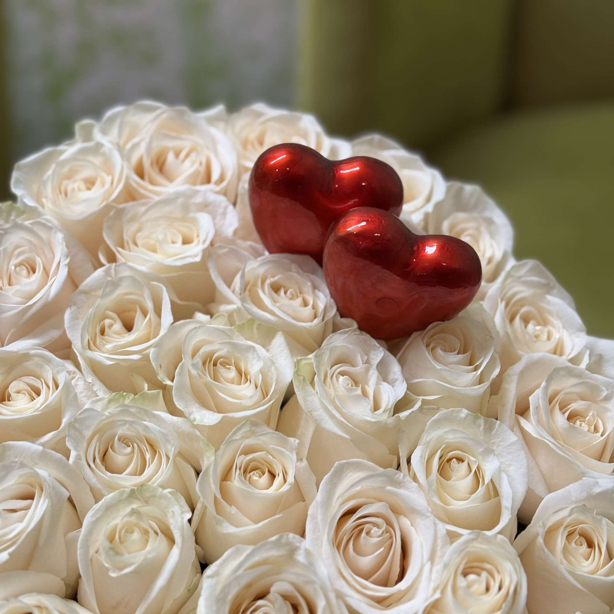 White rose bouquet topped with two red heart decorations