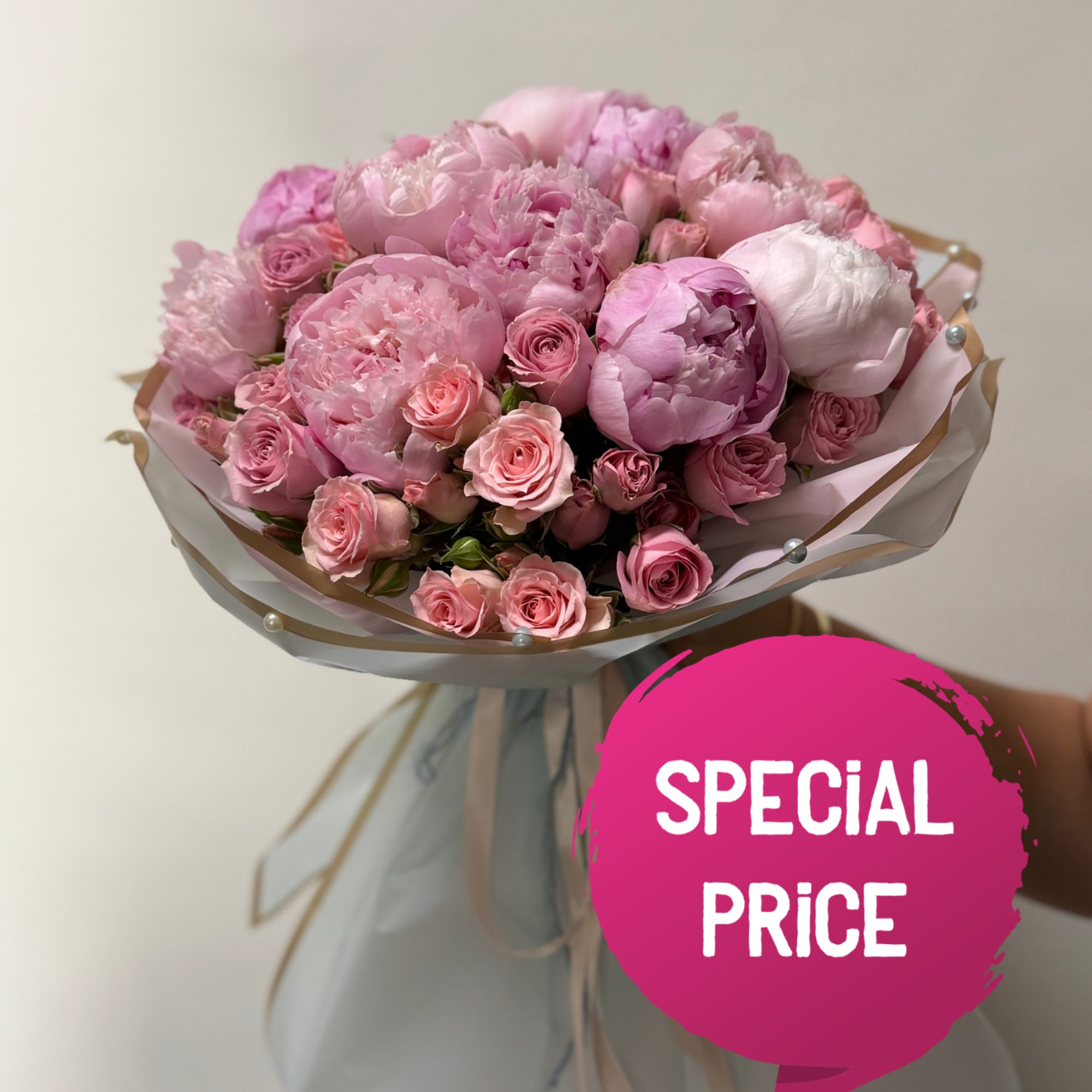 Pink bouquet of peonies and roses wrapped in pale paper