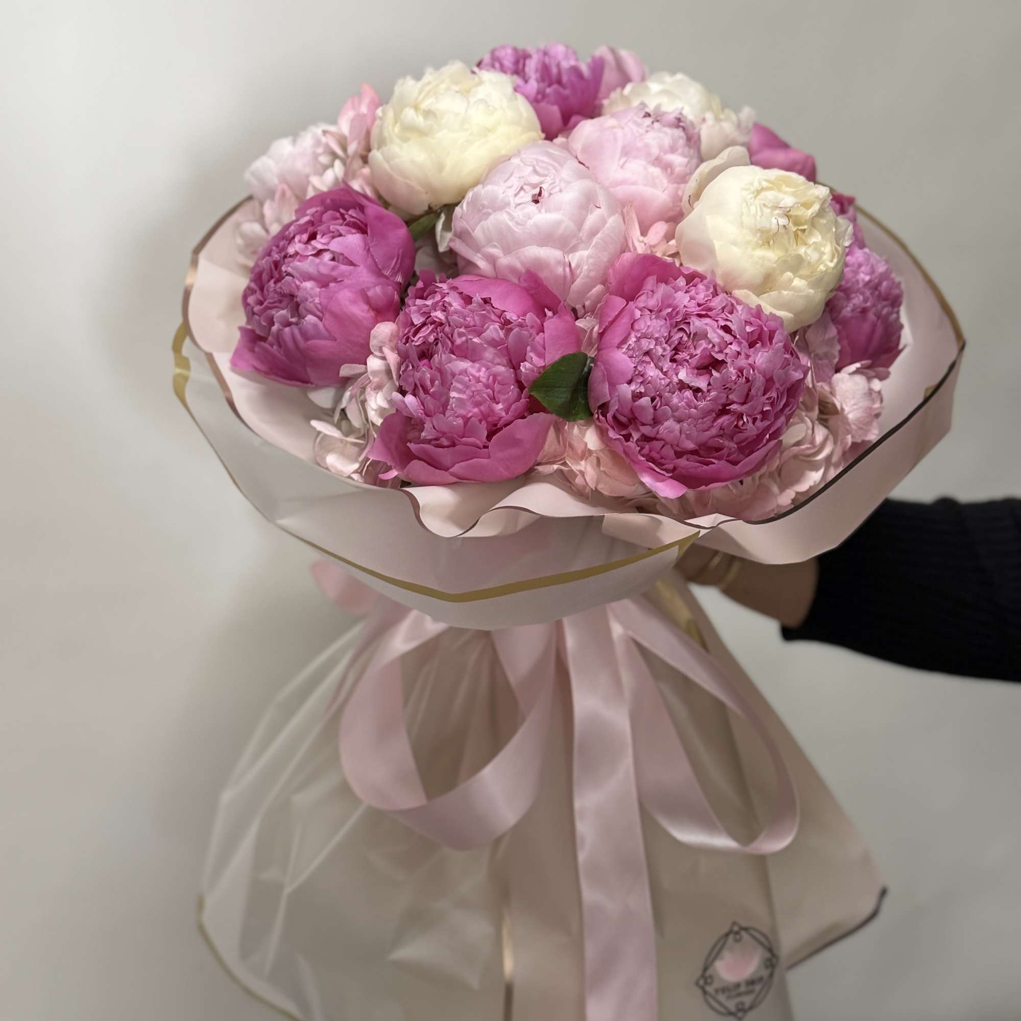 Pink and white peony bouquet wrapped in pale pink paper with ribbon