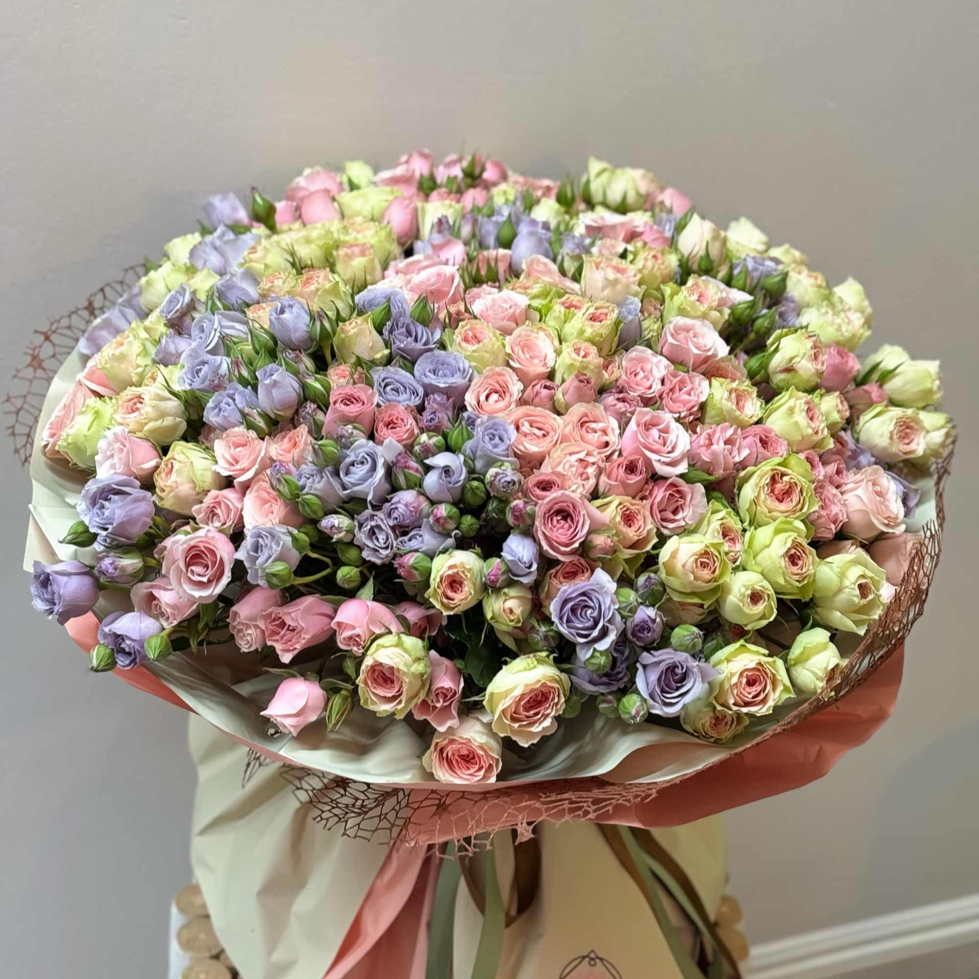 Large bouquet of pastel pink and lavender roses wrapped in paper
