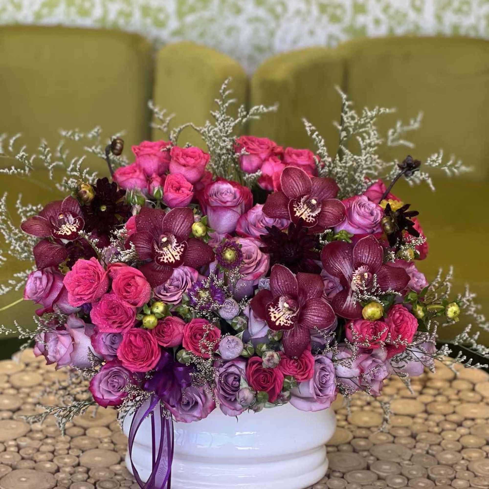 Pink and purple rose bouquet with dark orchids in a white vase
