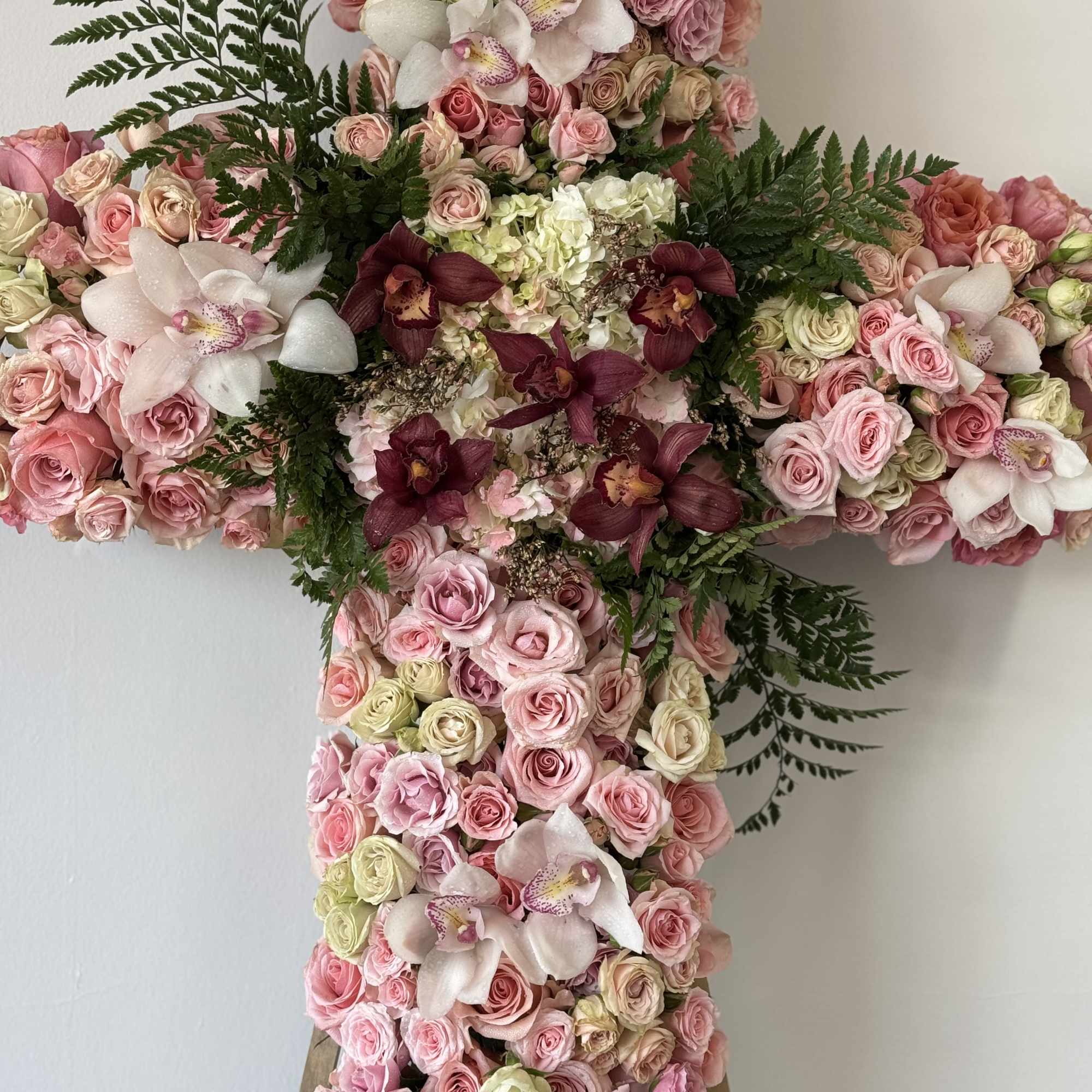 Cross-shaped floral arrangement with pink roses and white orchids