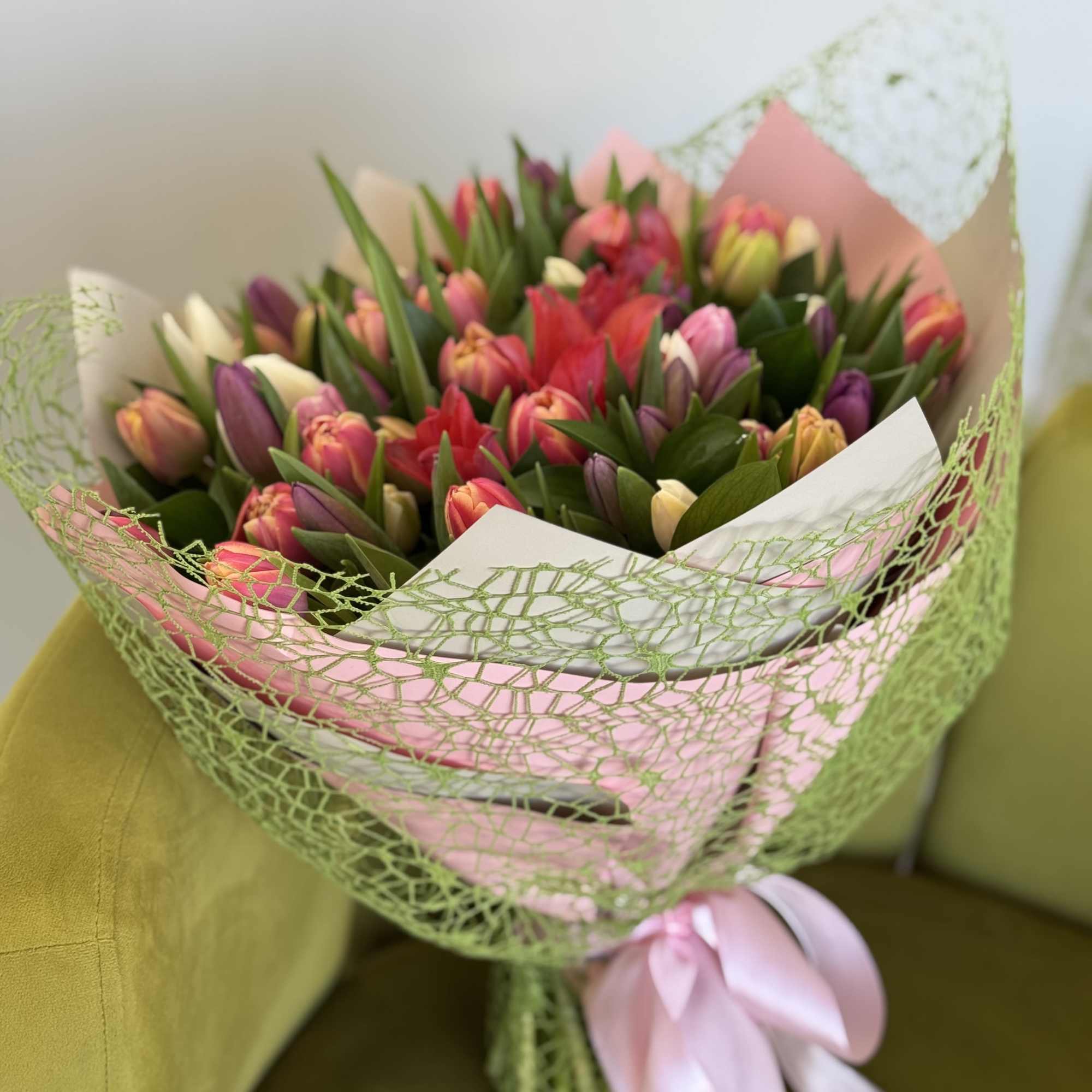 Bouquet of multicolored tulips wrapped in pink and green paper