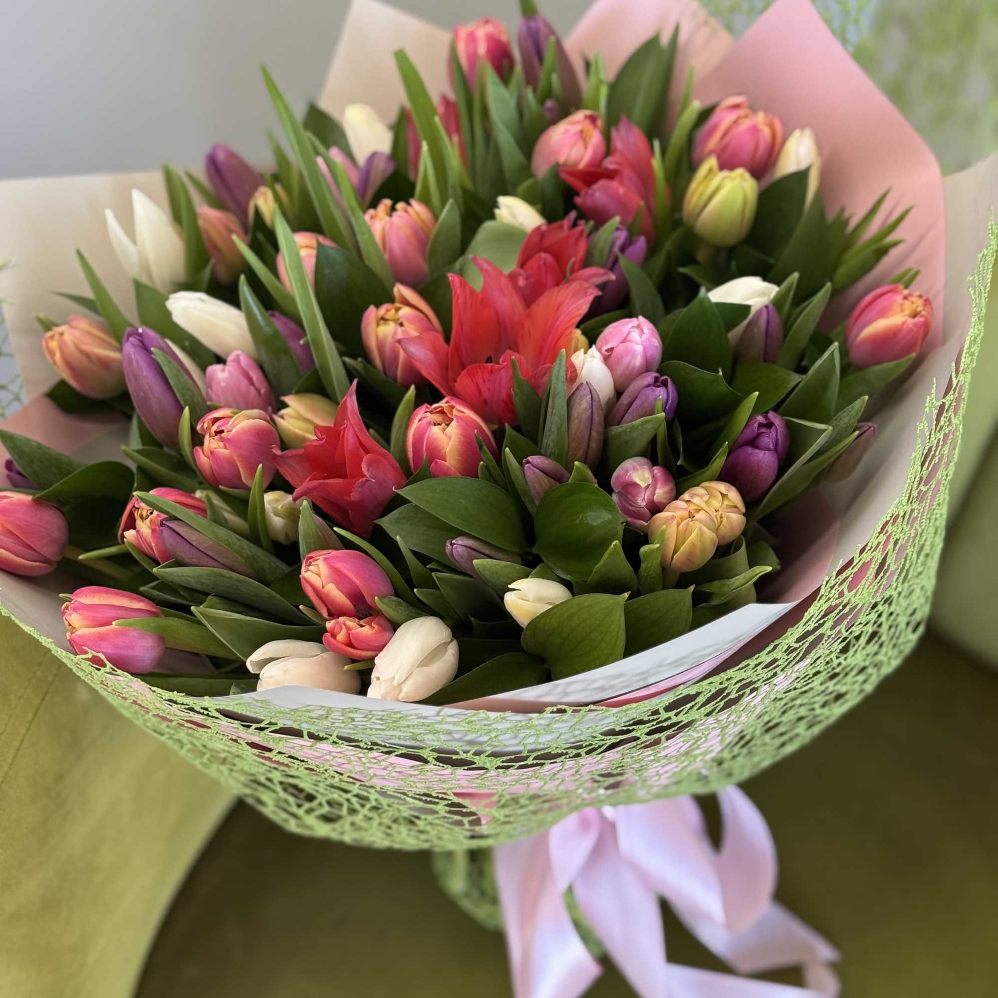 Bouquet of multicolored tulips wrapped in pink paper