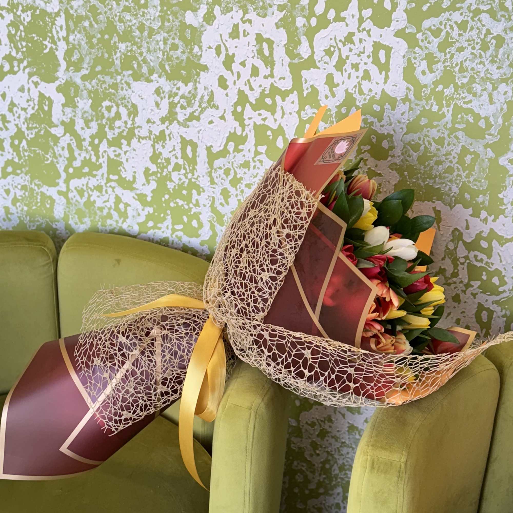 Wrapped bouquet of multicolored tulips with a yellow ribbon
