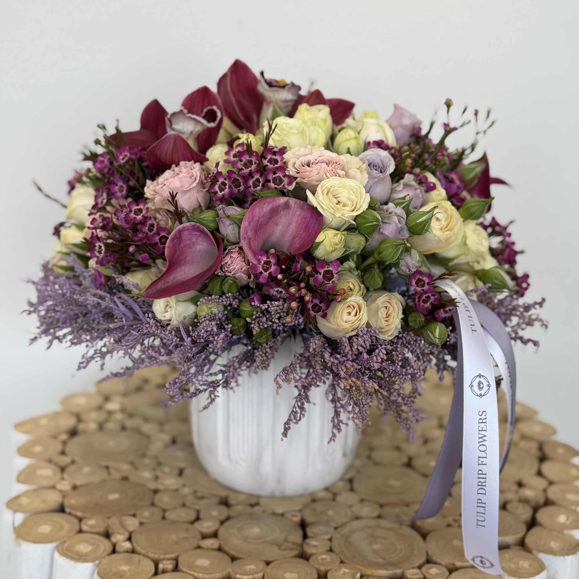 Bouquet of pink, cream, and purple flowers in a white vase