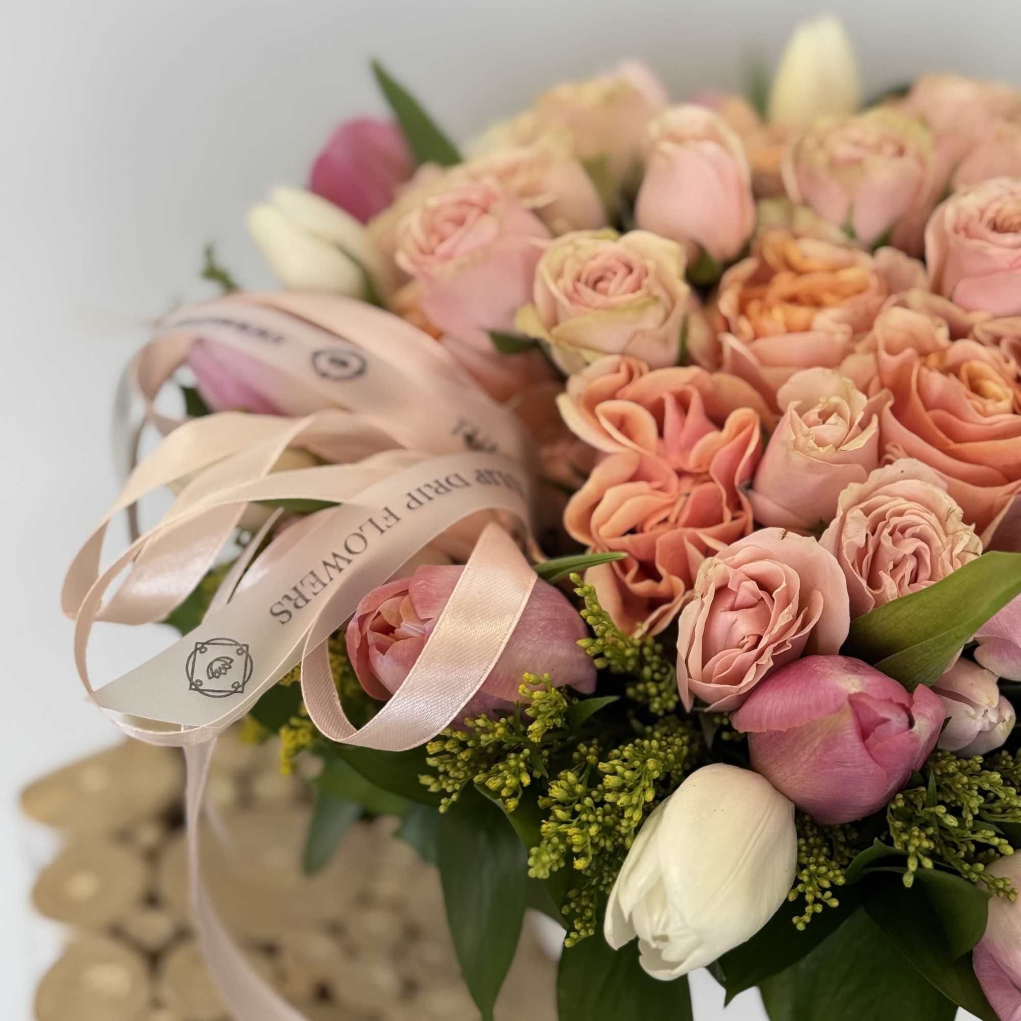 Bouquet of pink and peach roses with white tulips and a pink ribbon
