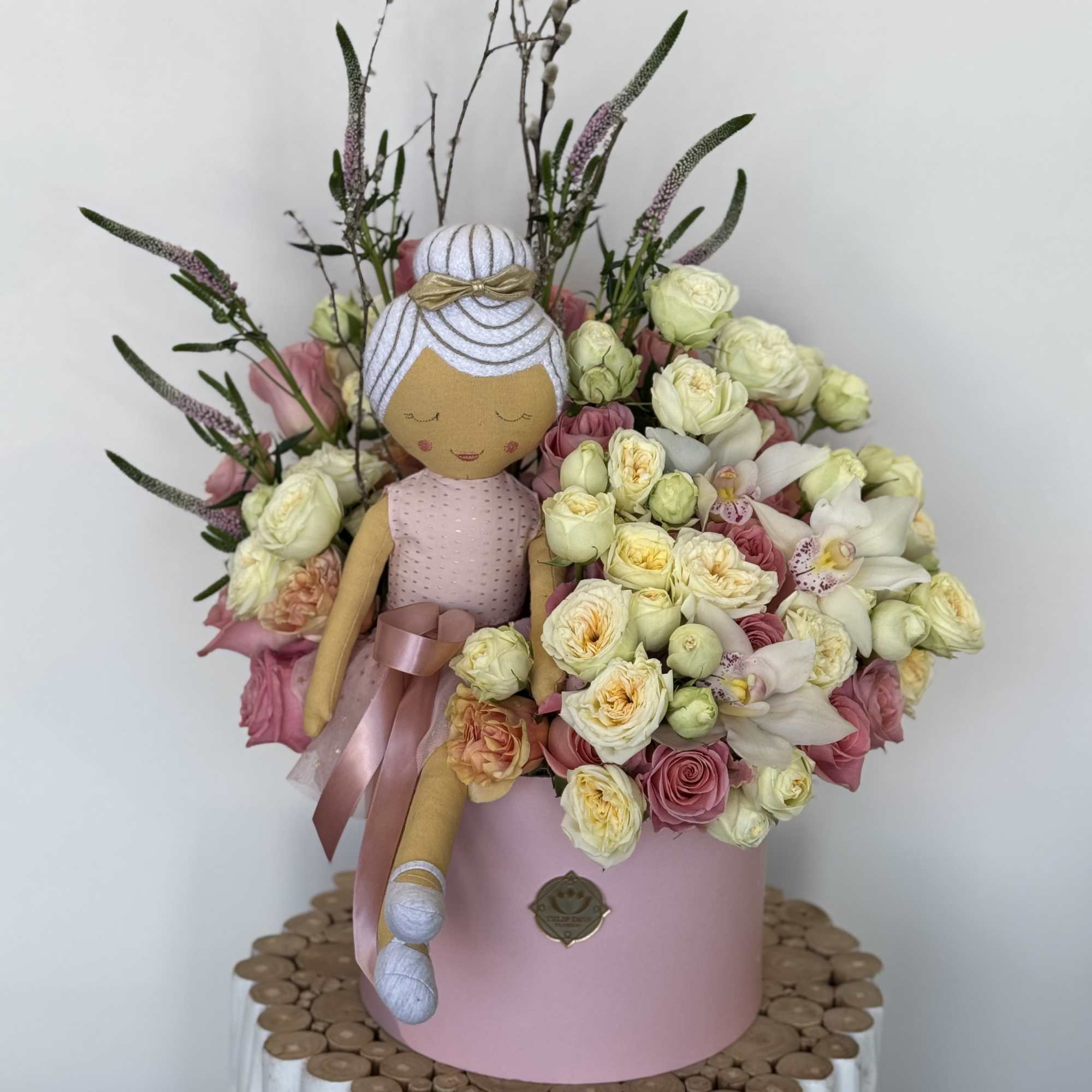 Bouquet with a fabric doll and pink and cream flowers in a pink box