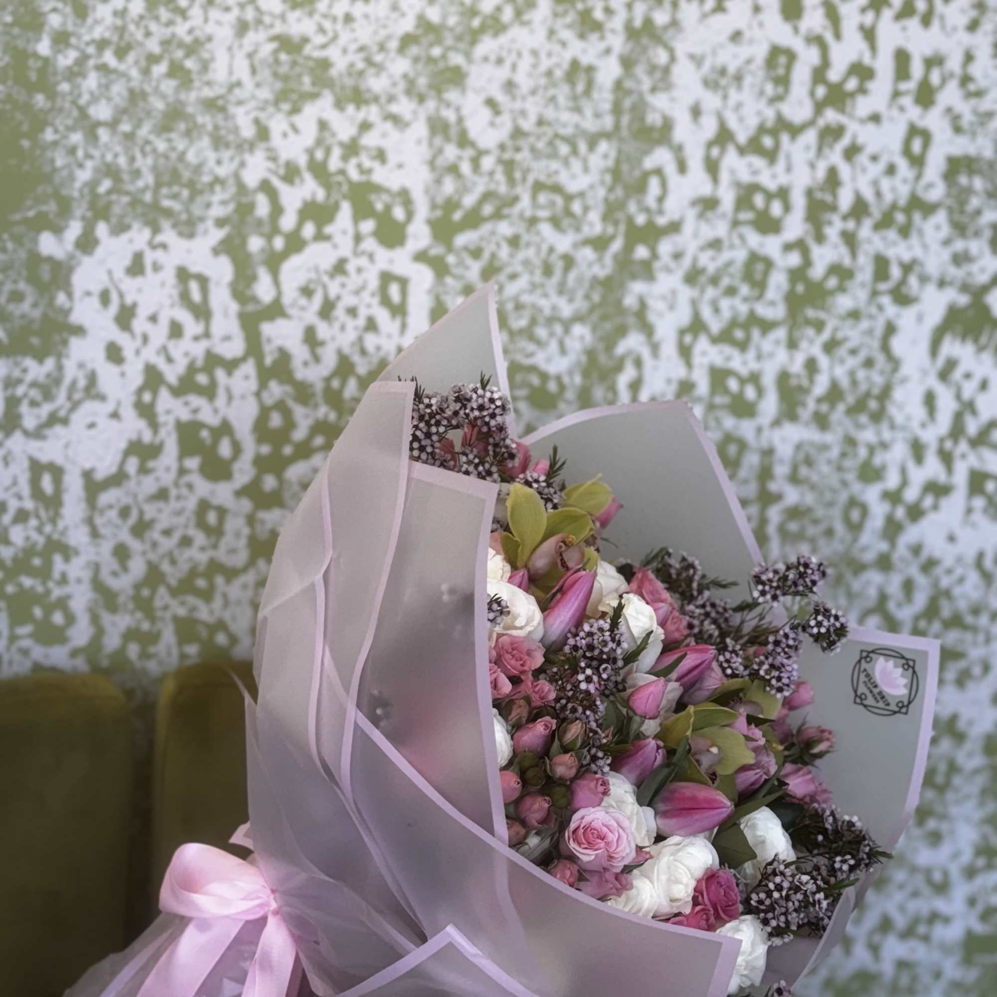 Pink and white bouquet wrapped in translucent paper with a pink ribbon
