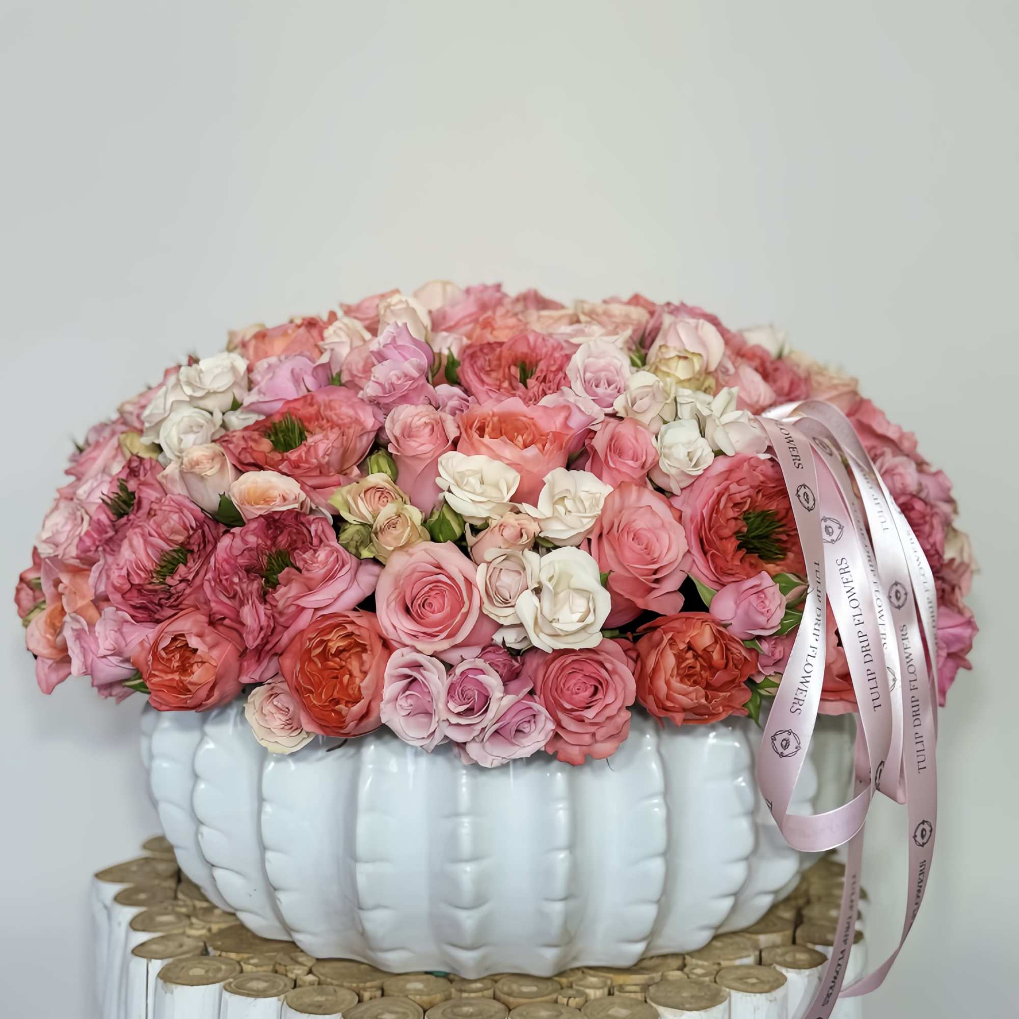 Pink and white rose arrangement in a white pumpkin-shaped vase with ribbon