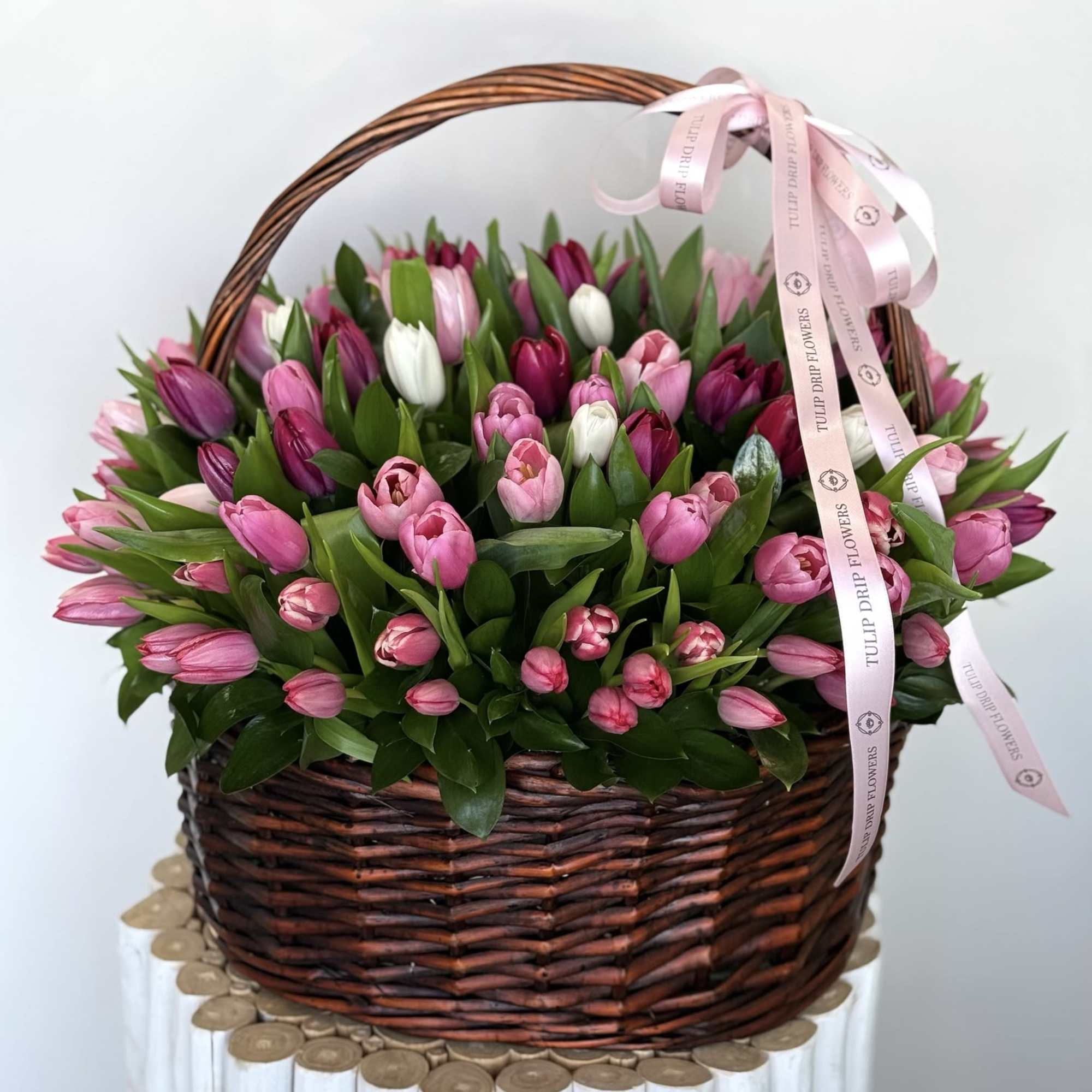 Basket of pink and white tulips with a pink ribbon bow
