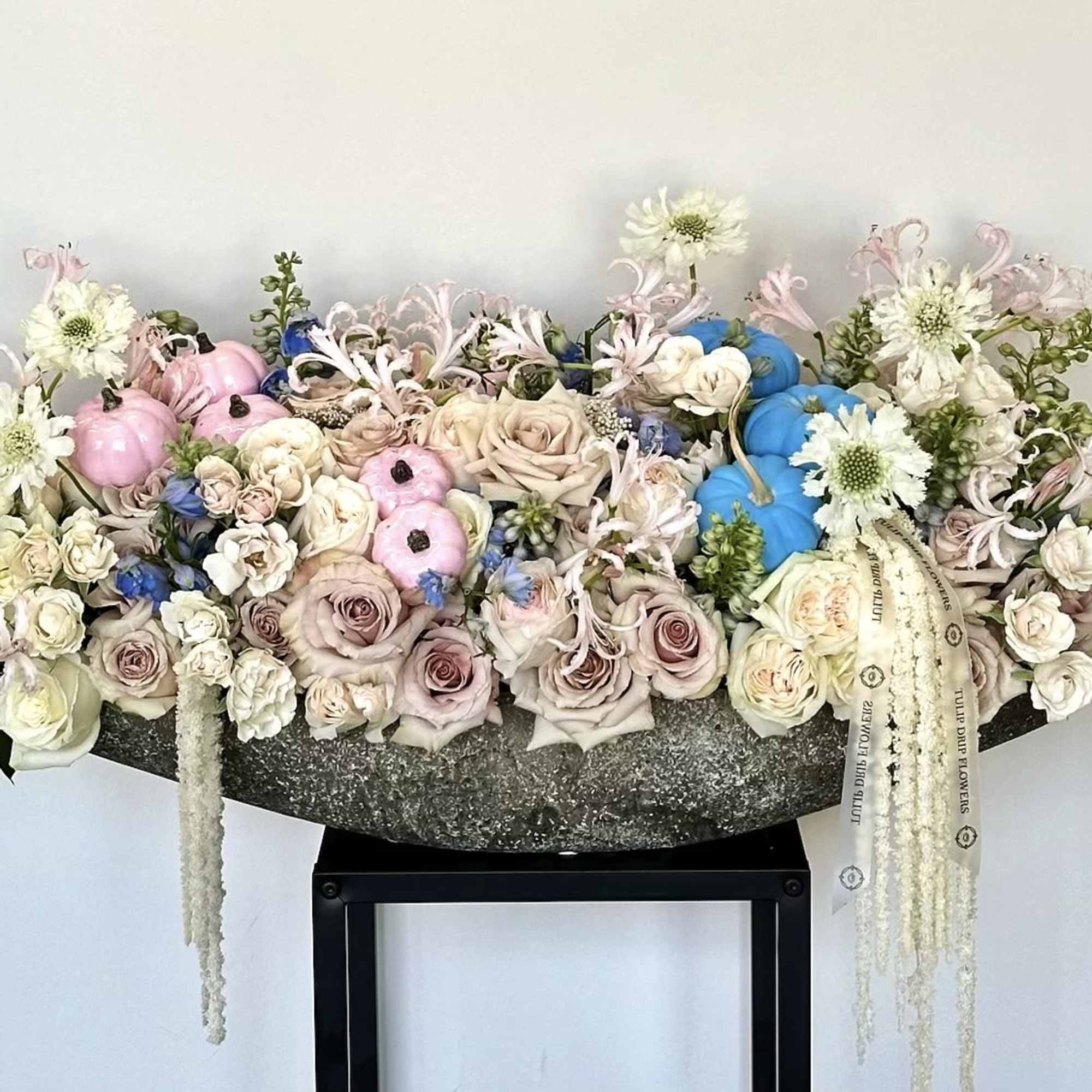 Large pastel floral arrangement with roses, white blooms, and decorative pumpkins
