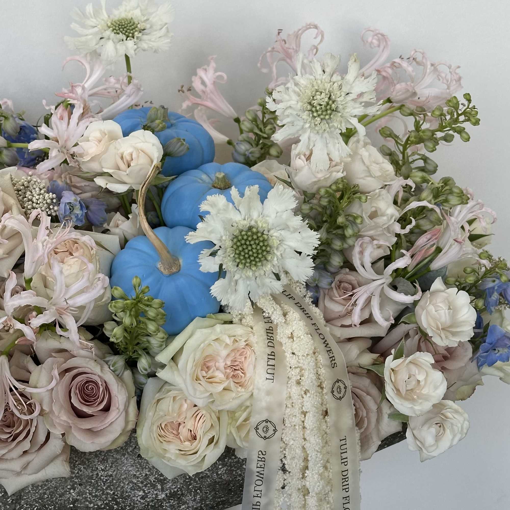 Pastel bouquet with blue pumpkins, pale roses, and white flowers