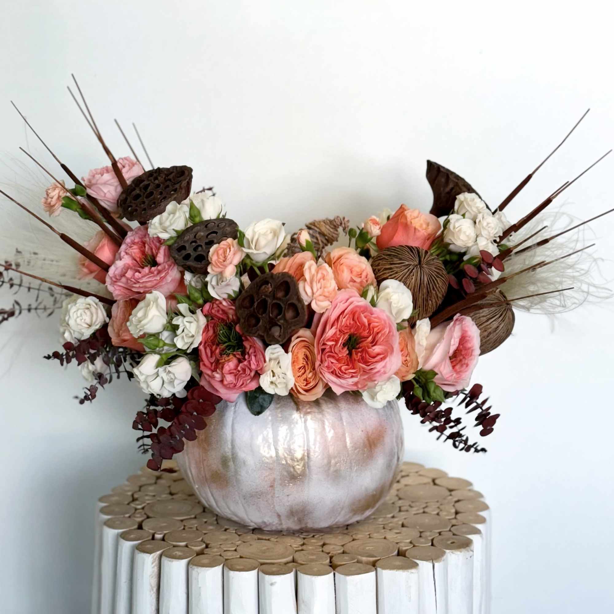 Pink and white floral arrangement in a metallic pumpkin vase