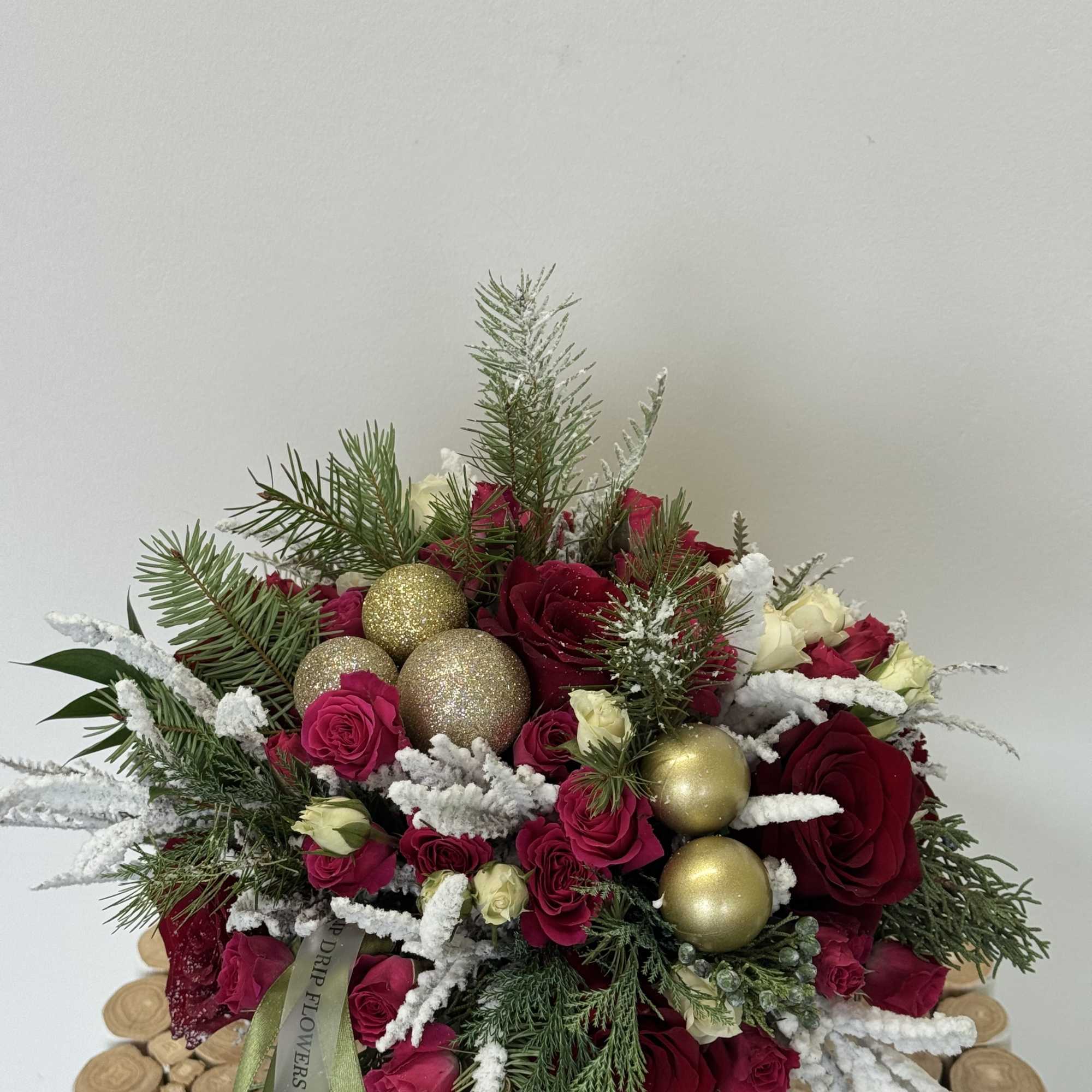 Red and pink rose arrangement with gold ornaments and snowy pine accents