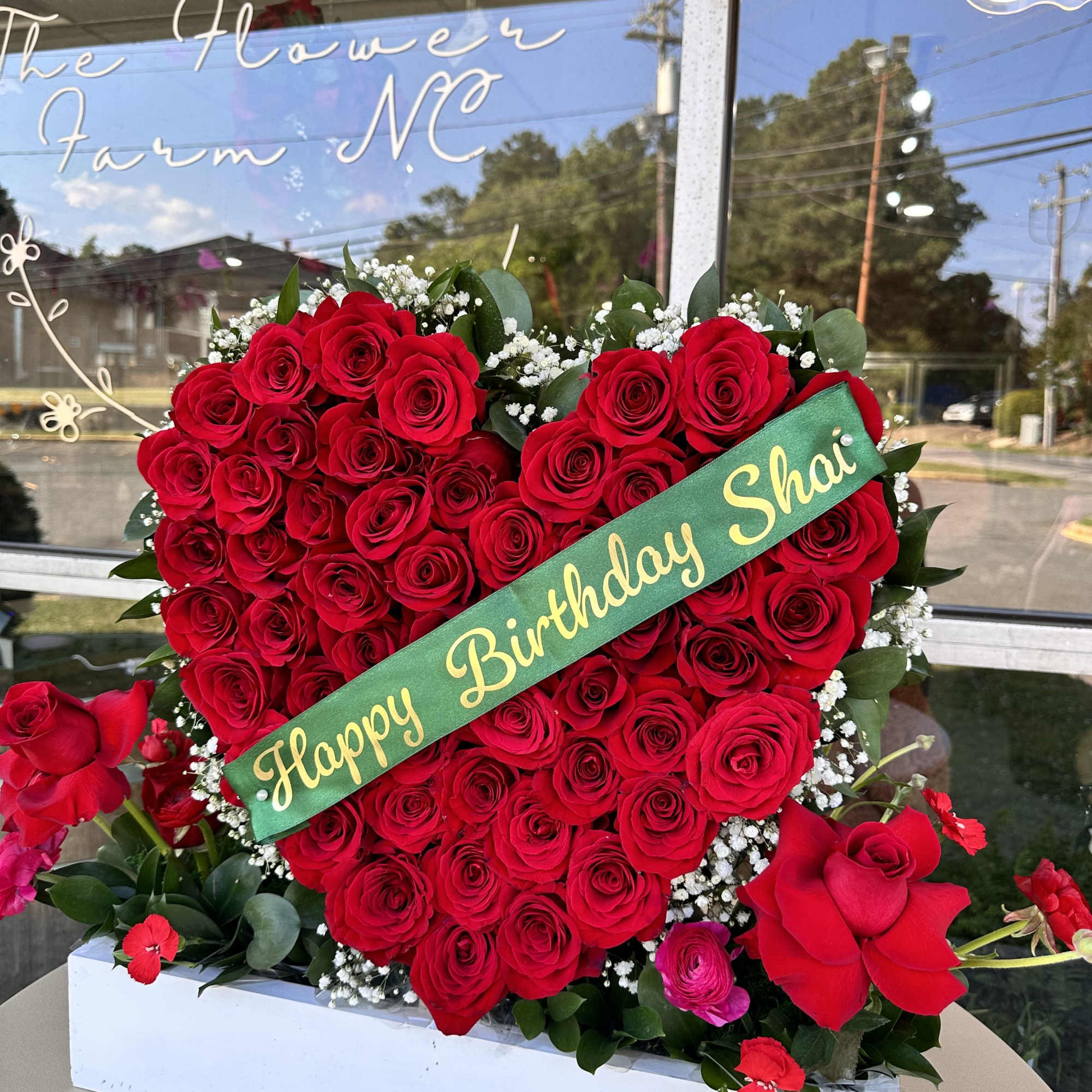 Heart-shaped red rose arrangement with a birthday sash in a white box