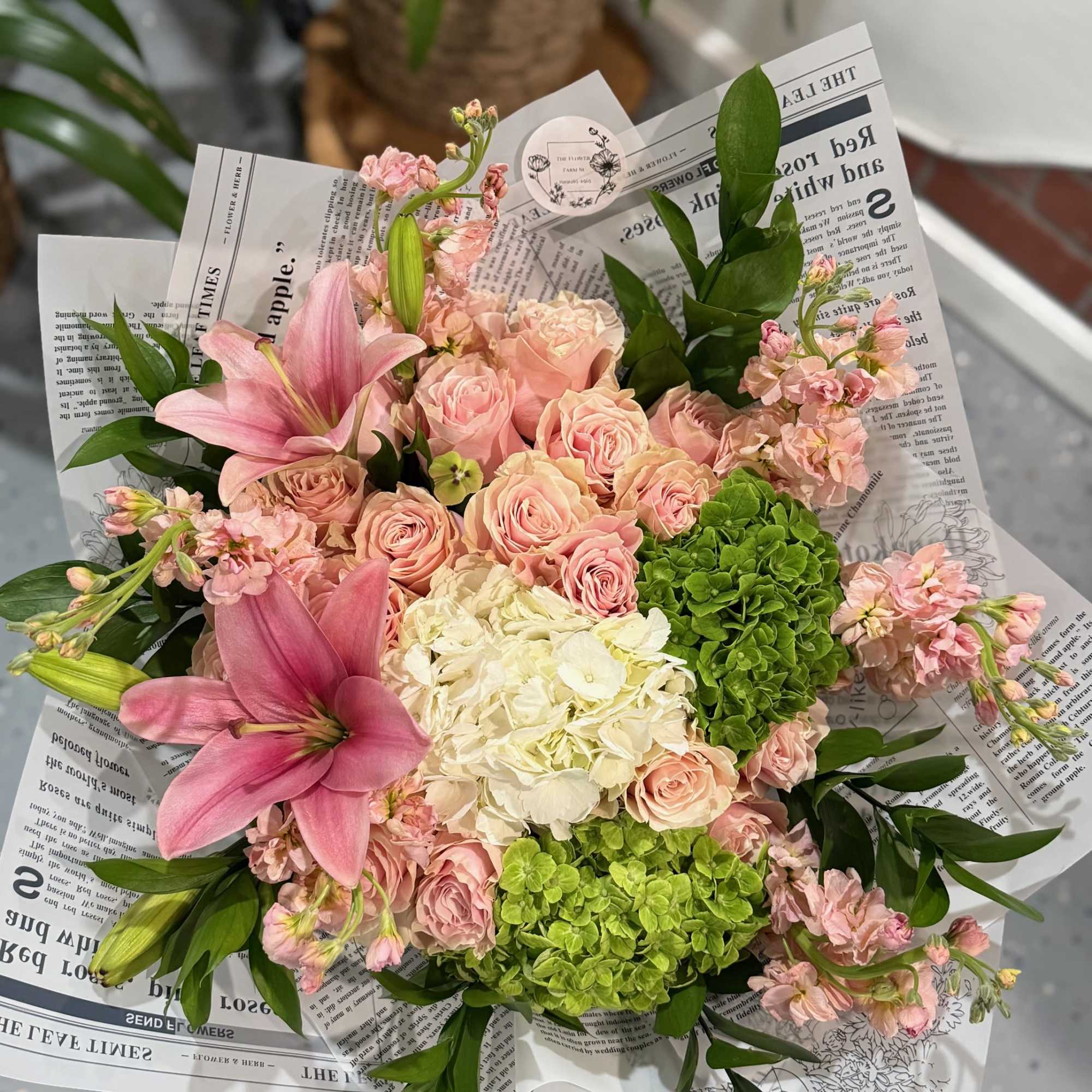 Pink lilies and roses with green hydrangeas in wrapped bouquet