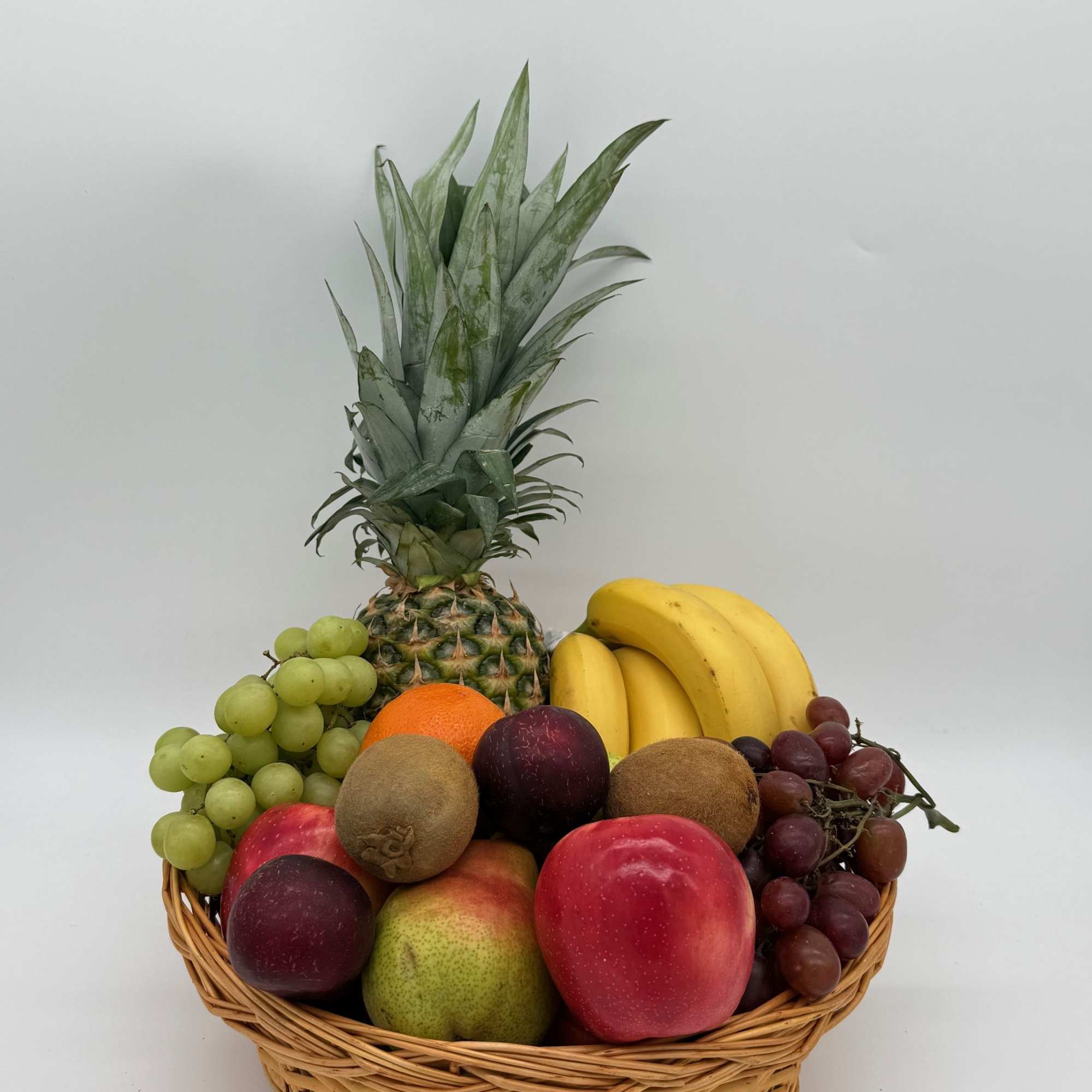 Fruit basket with pineapple, bananas, grapes, kiwi, oranges, apples, and pears