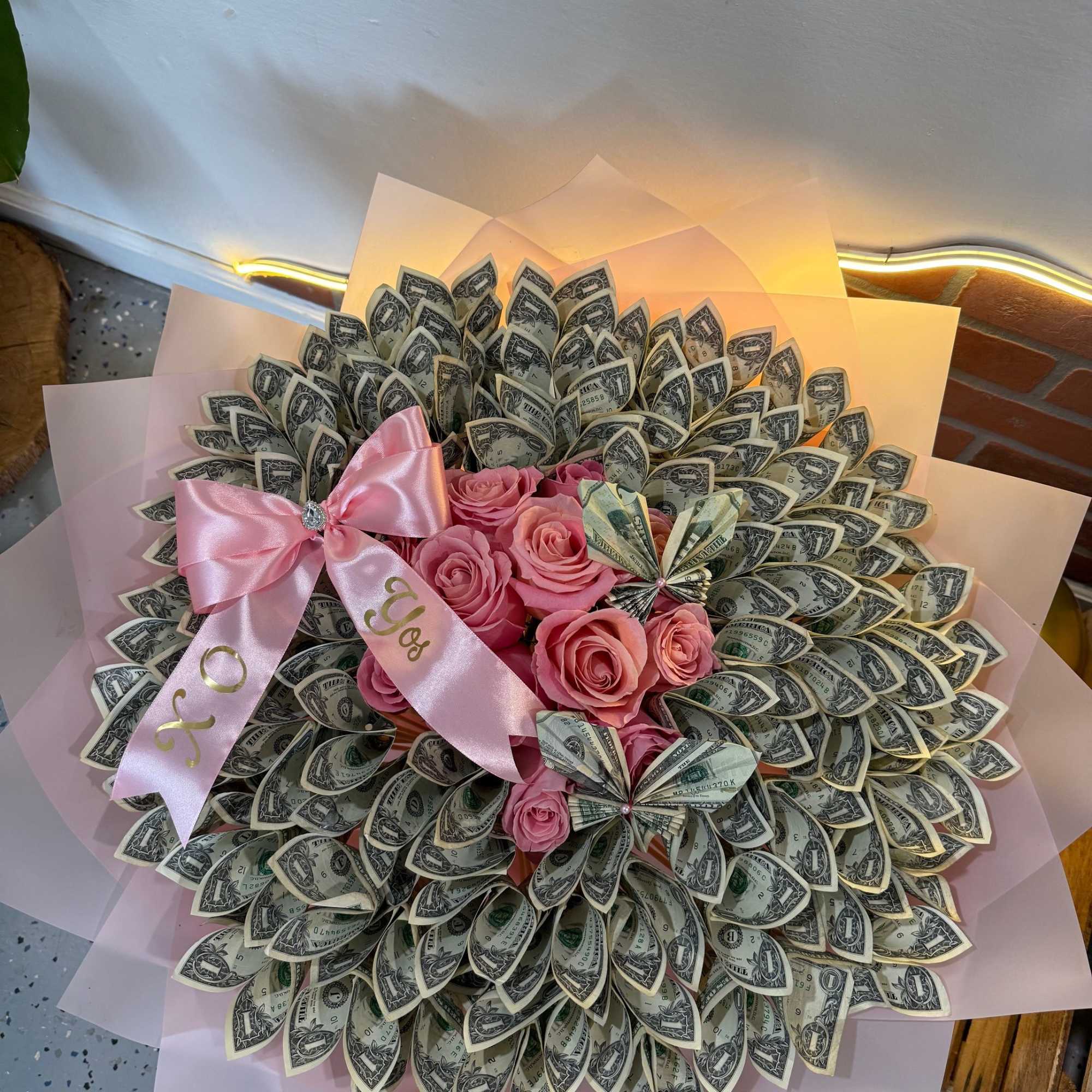 Bouquet of pink roses wrapped with dollar bills and pink ribbon