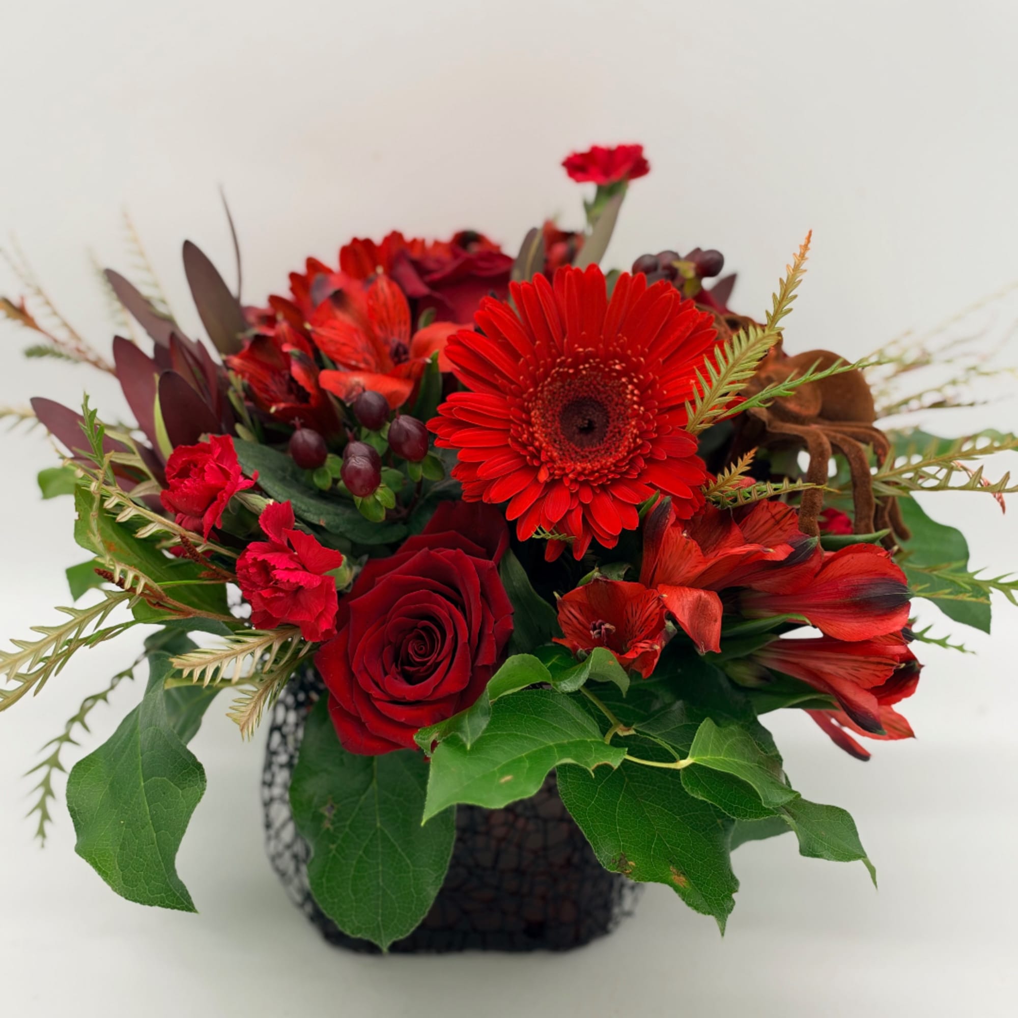 Red roses and gerbera daisies arranged in a black vase