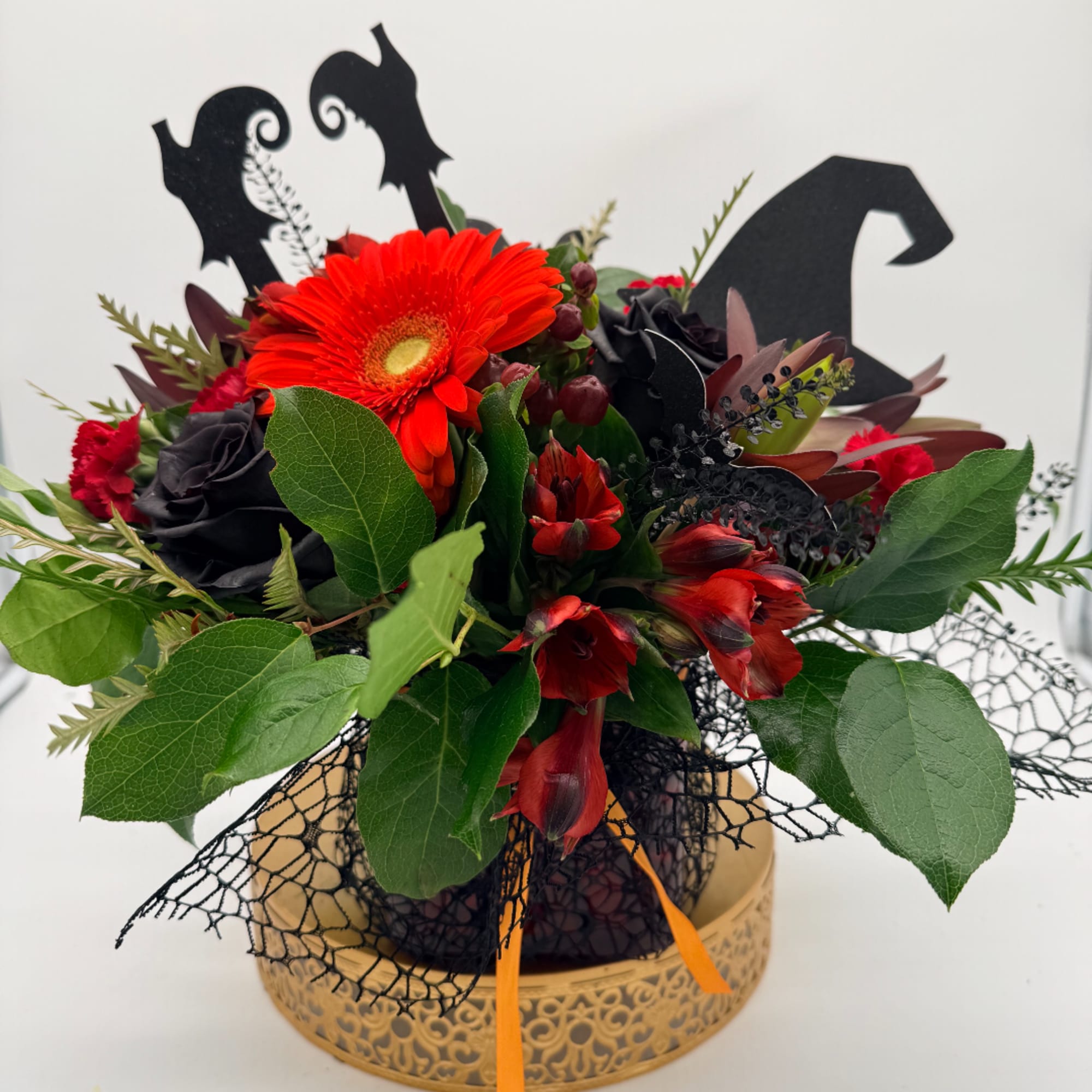 Red and black floral arrangement in a decorative gold container