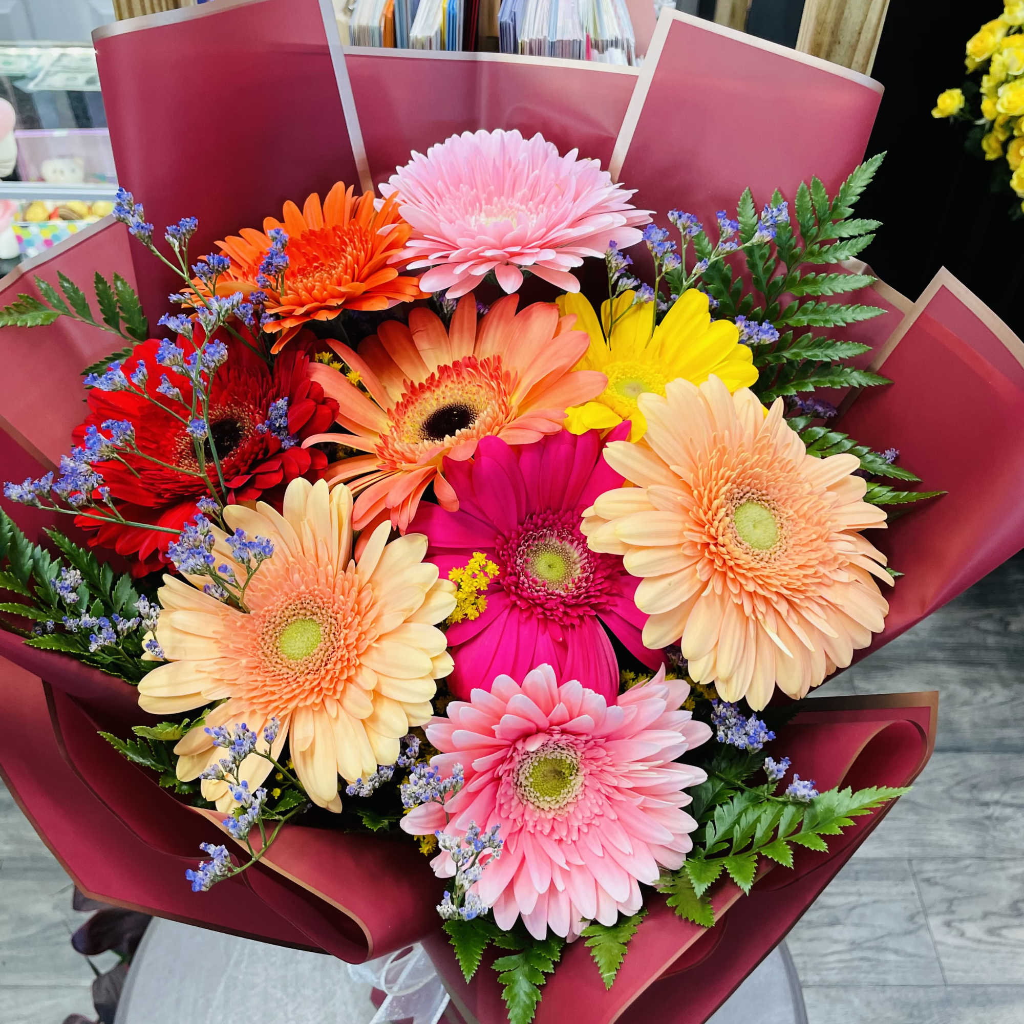 Bright mixed gerbera daisy bouquet wrapped in burgundy paper