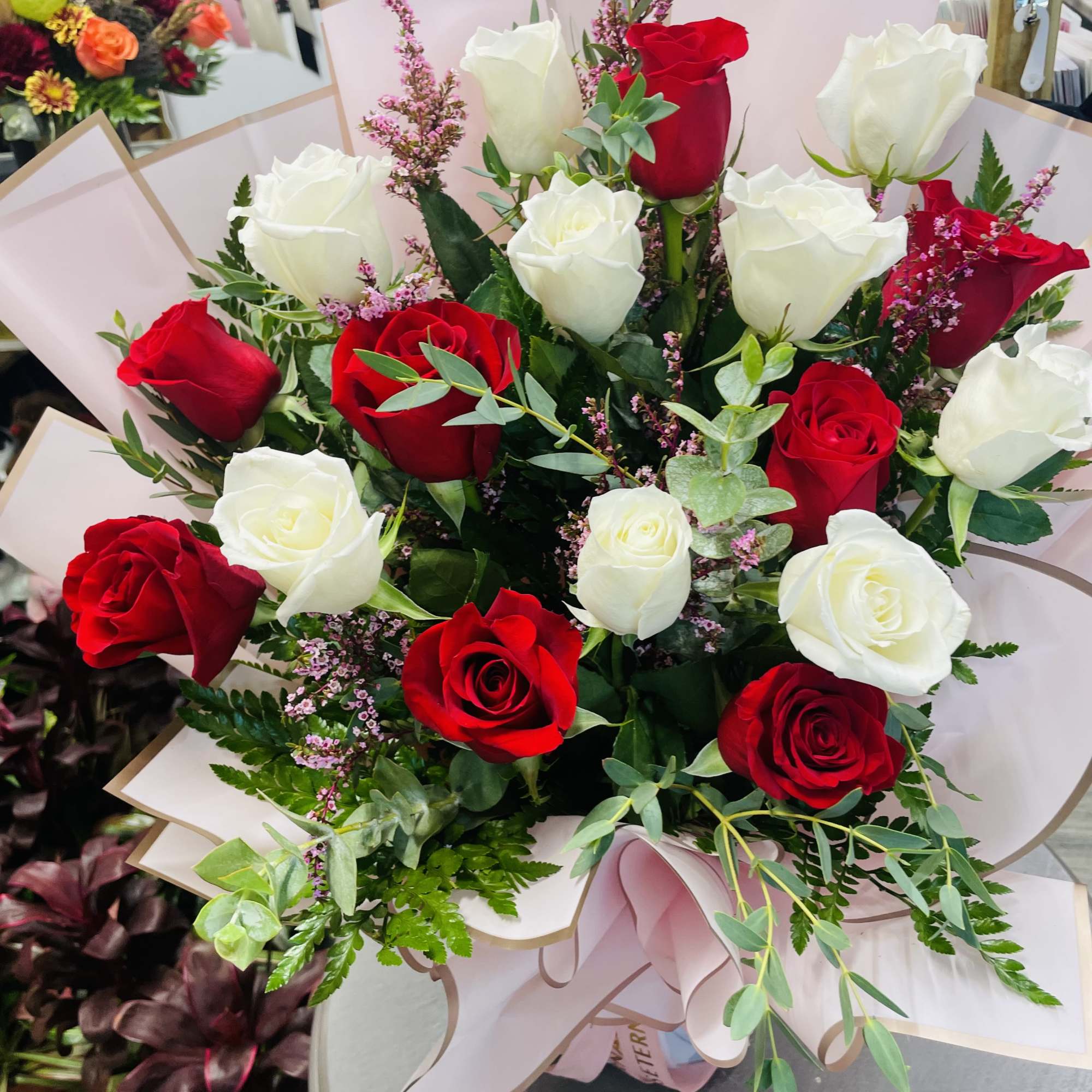 Bouquet of red and white roses wrapped in pale pink paper