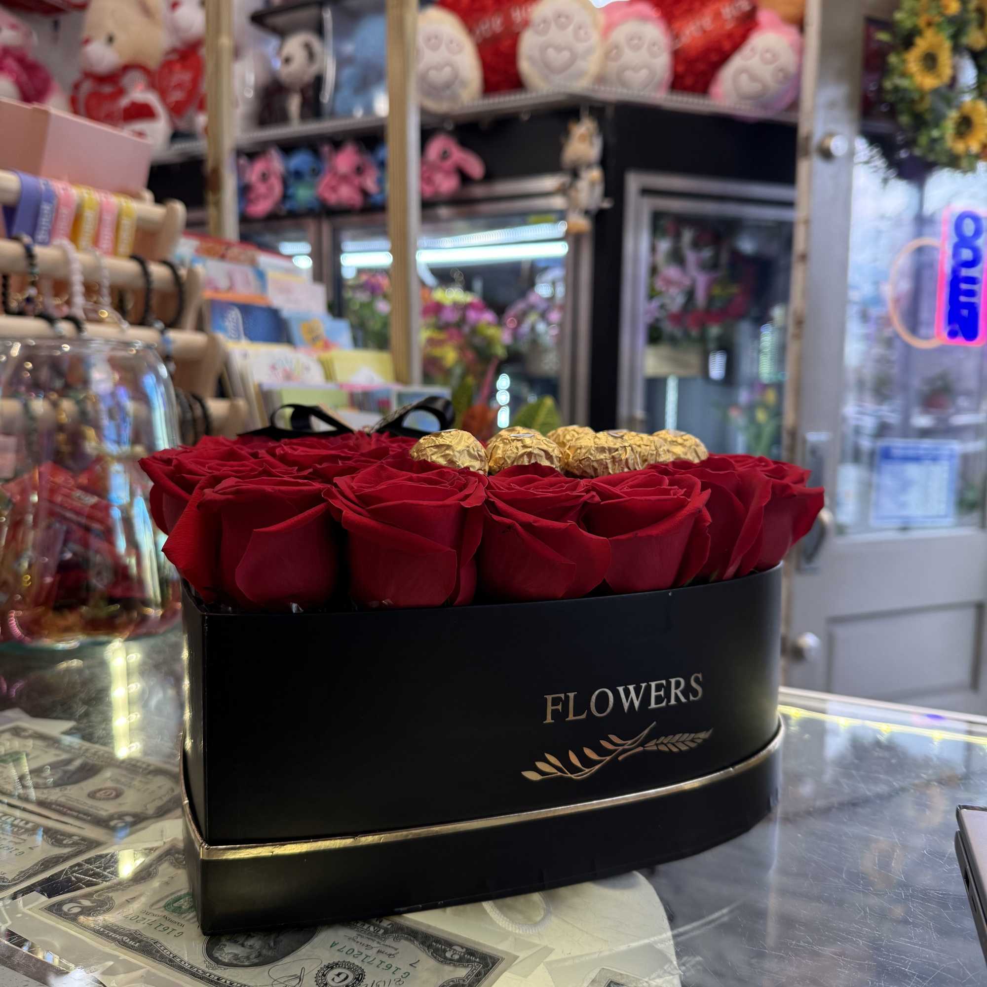Red roses in a black oval box with gold-wrapped chocolates