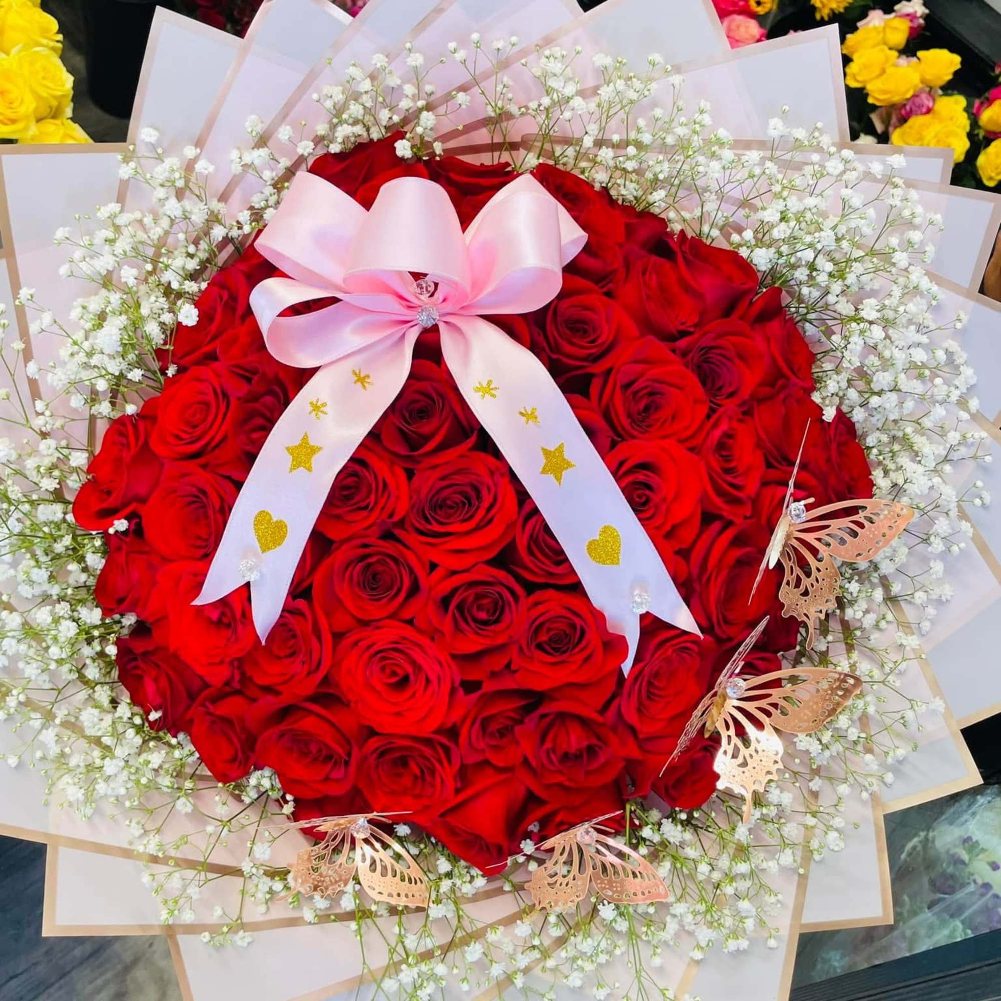 Large bouquet of red roses with white baby's breath and a pink ribbon