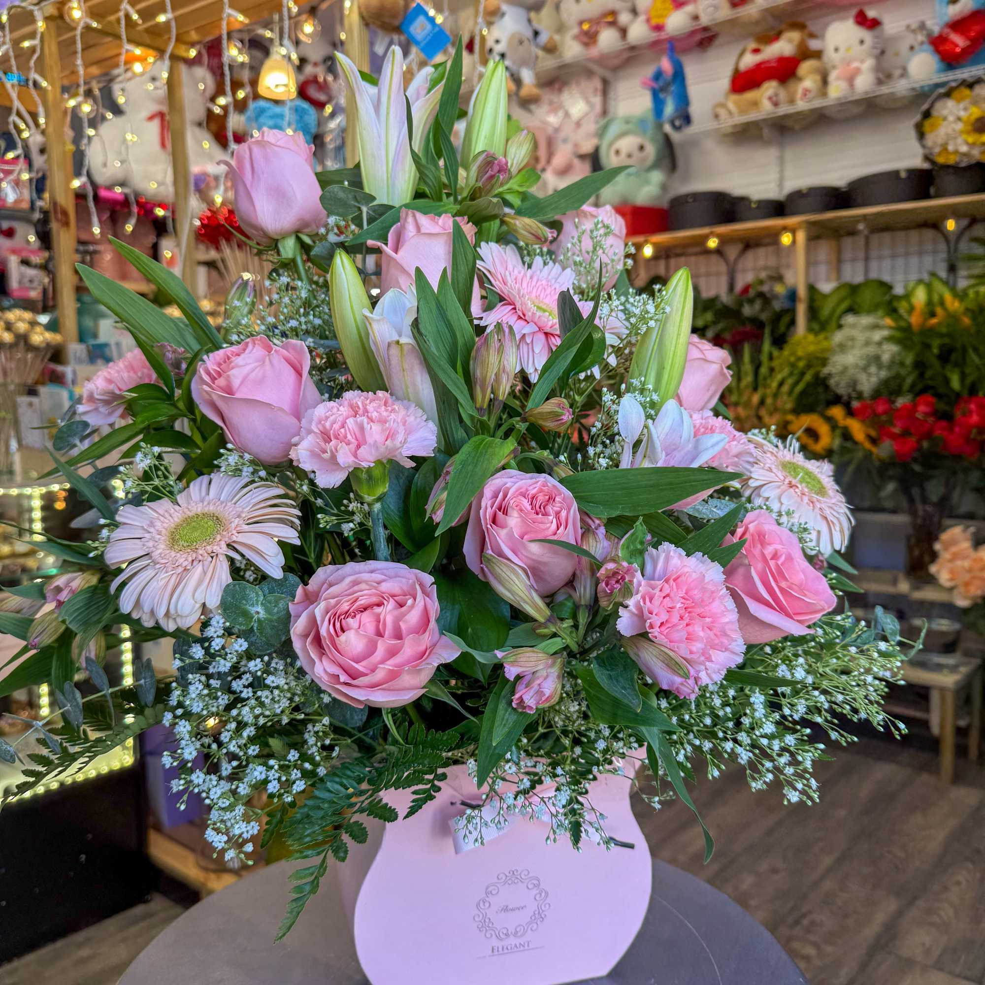 Pink roses and lilies arranged in a pastel pink box