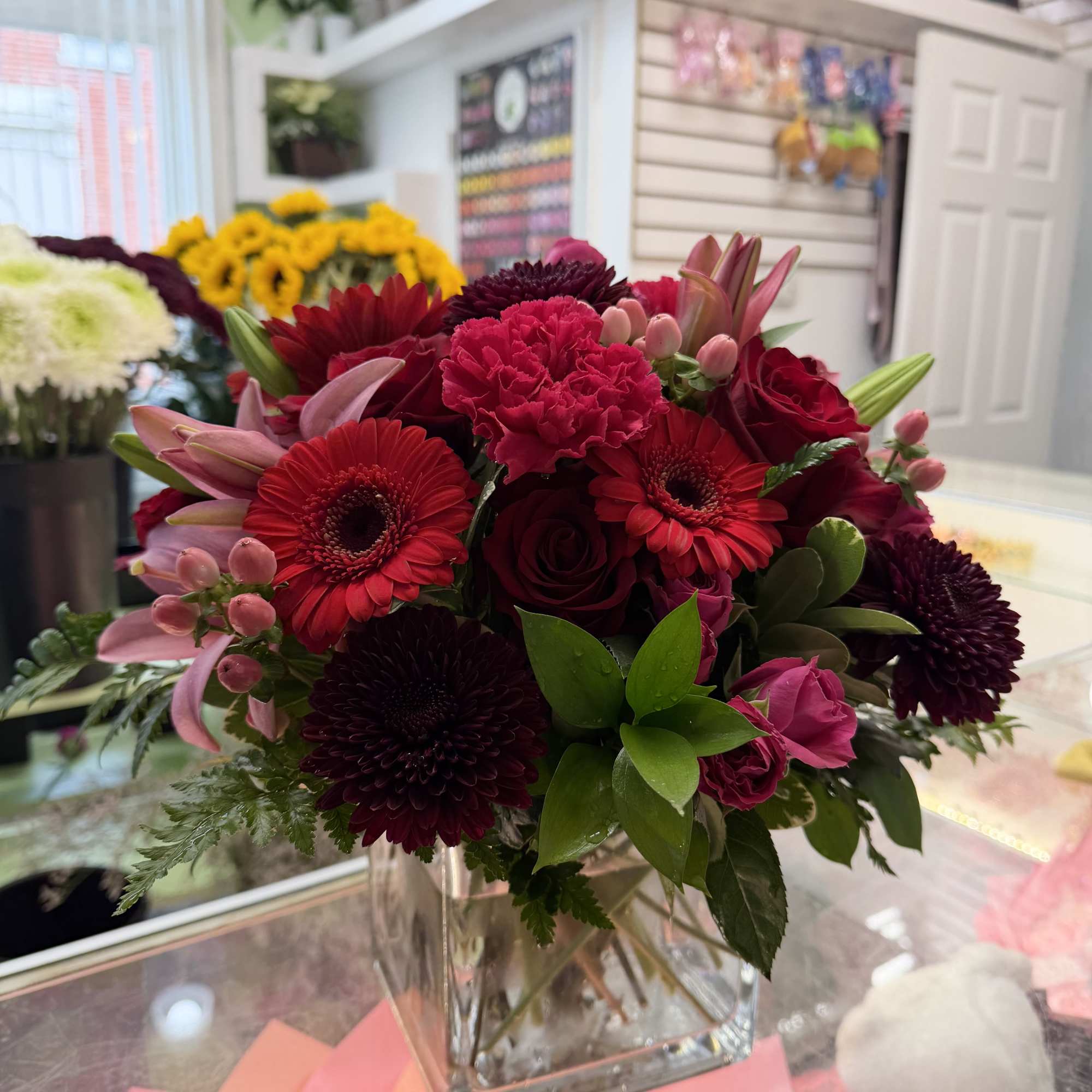 Bouquet of red and pink flowers in a clear square vase