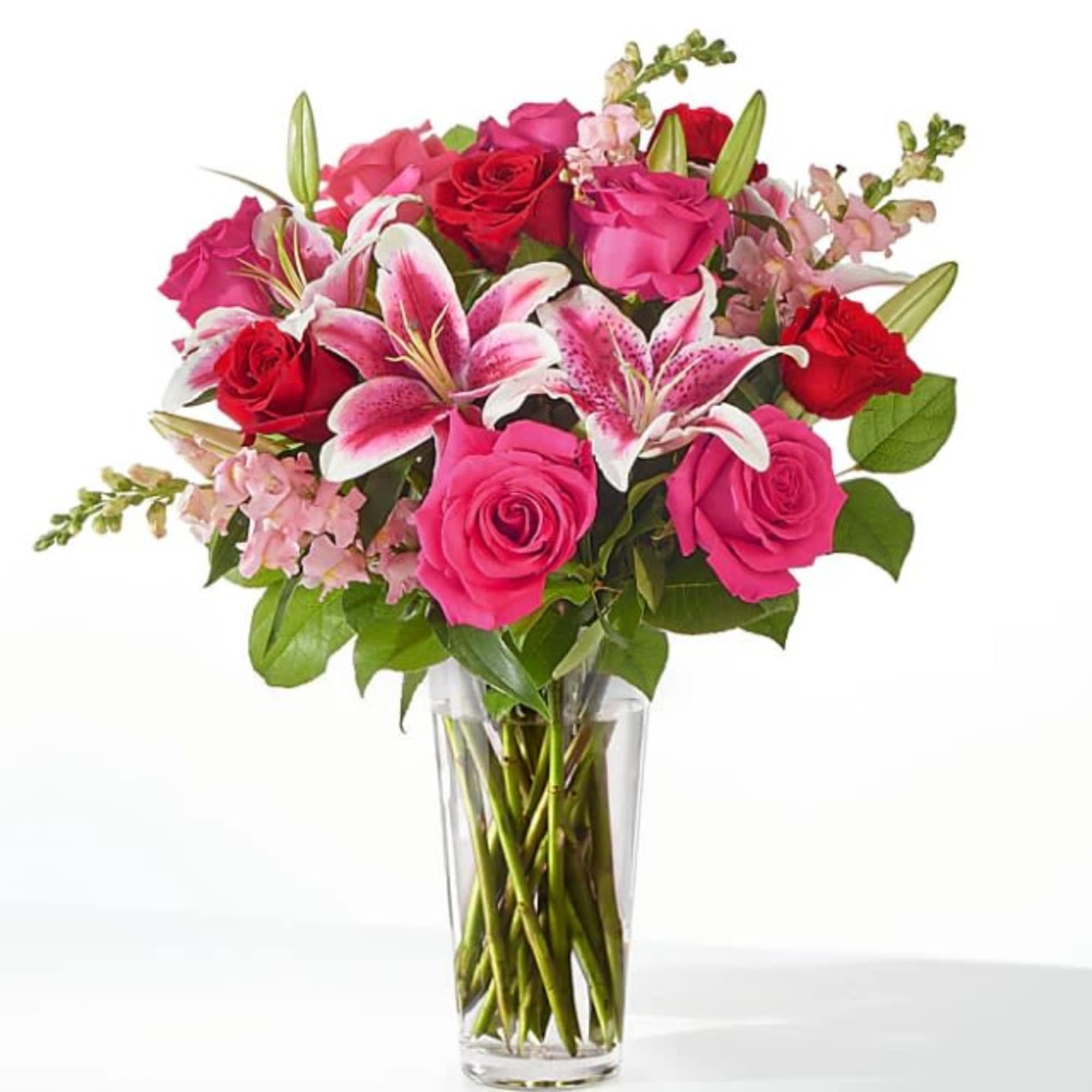 Tall glass vase of red and hot pink roses with pink lilies and snapdragons.