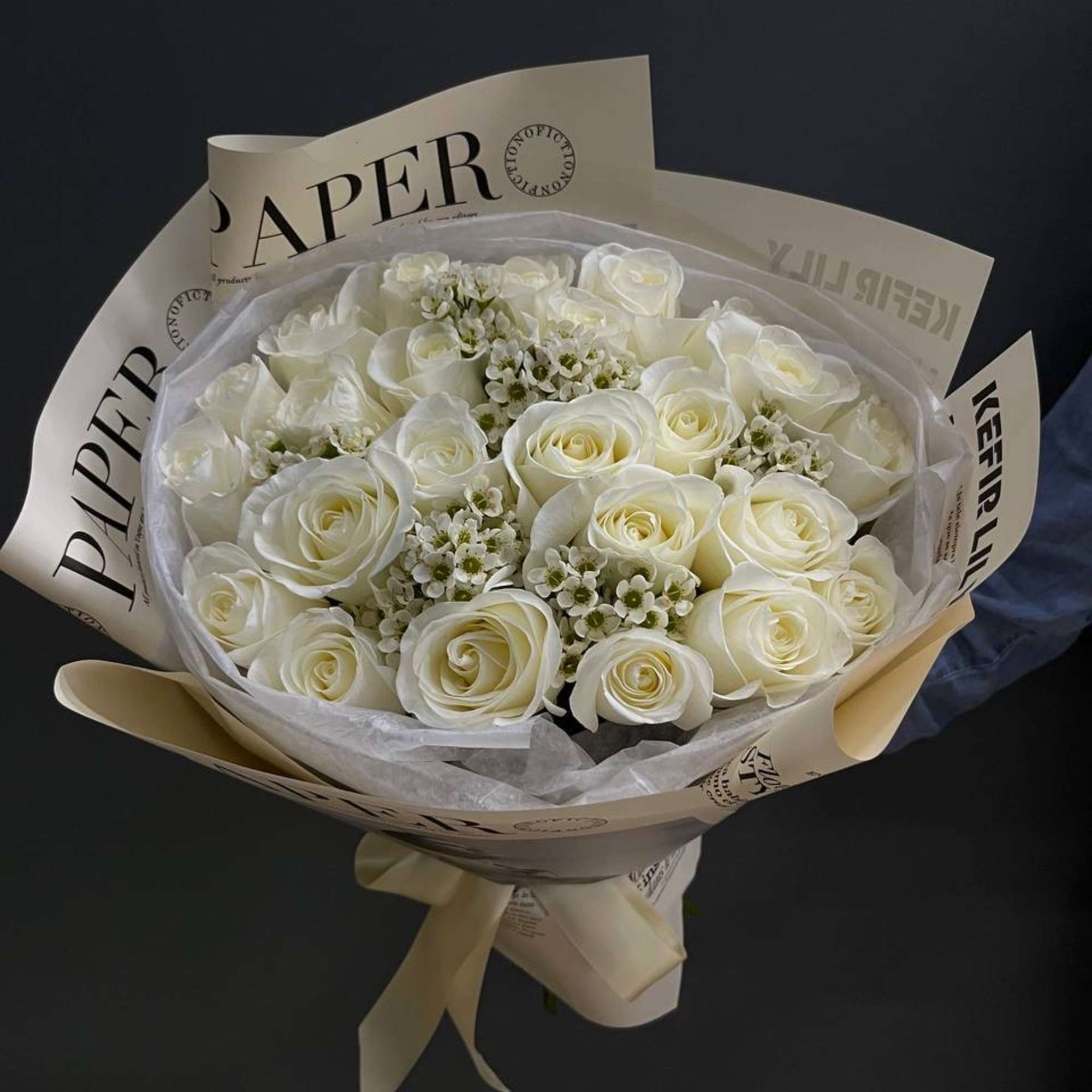 Bouquet of white roses wrapped in cream paper with a ribbon
