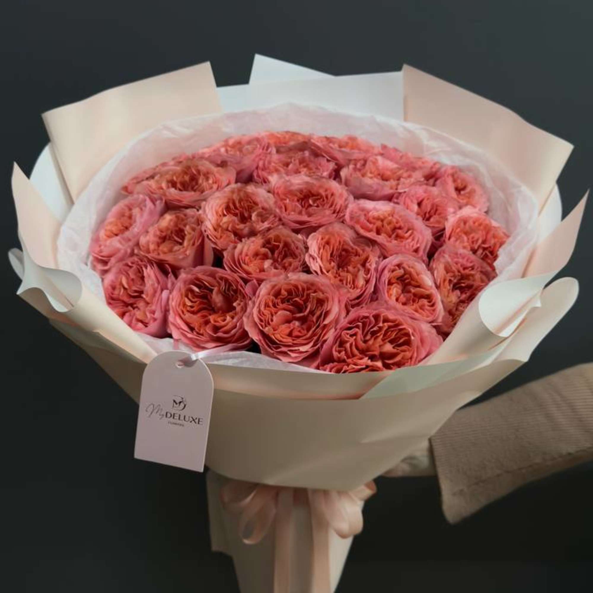 Bouquet of coral-pink roses wrapped in pale paper