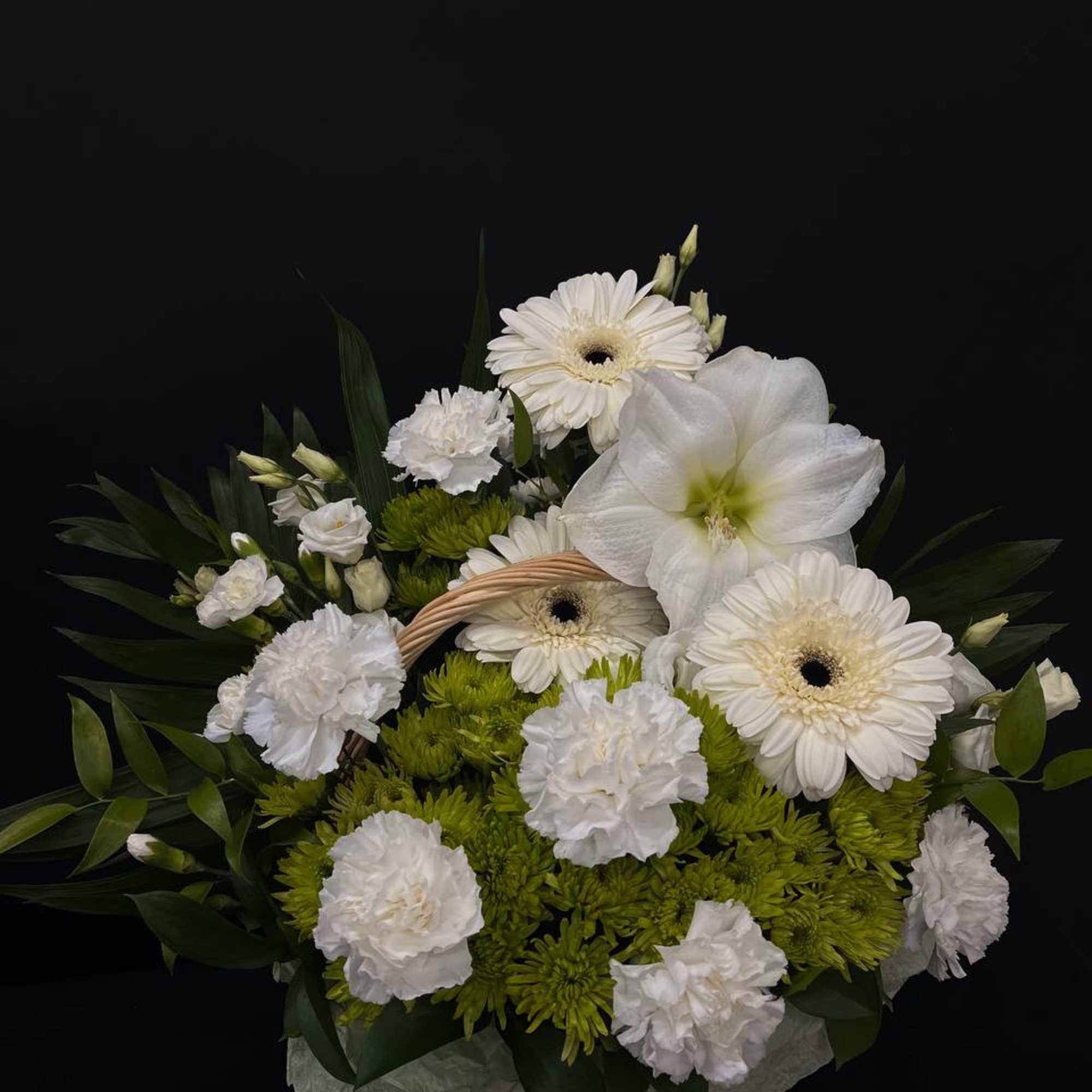 White flowers and green blooms arranged in a wicker basket