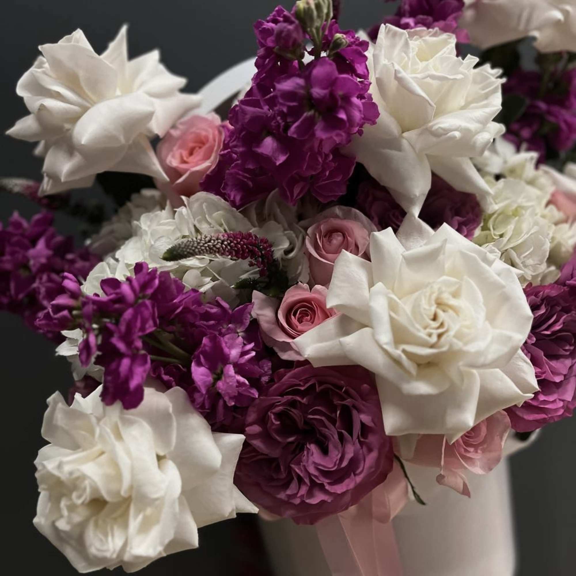 Bouquet of white and pink roses with purple blooms in a white hatbox