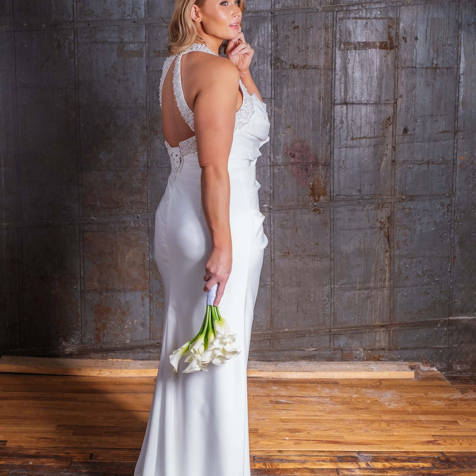 Bride in a white gown holding a small bouquet of white calla lilies, photo 2 of 4