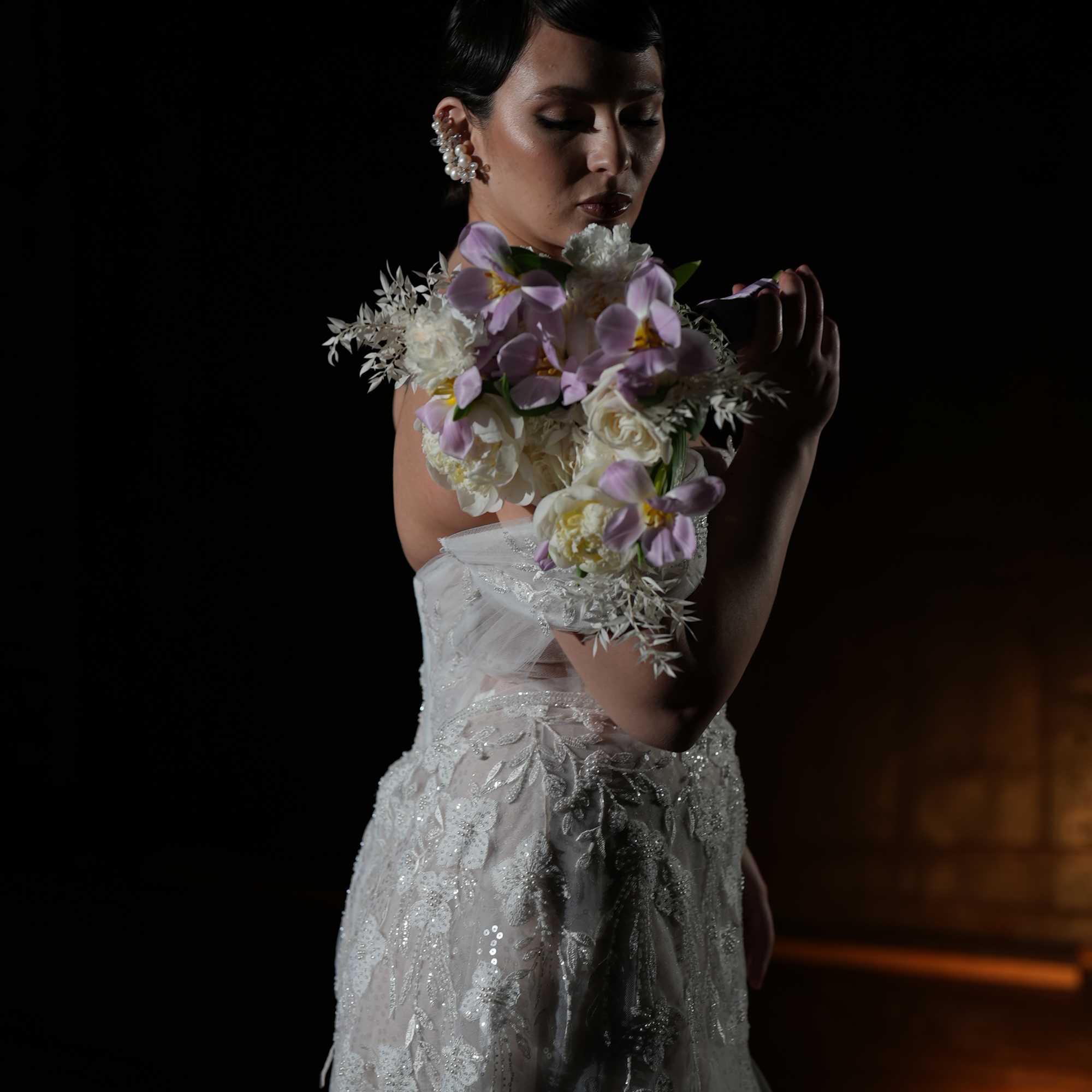 Bride in a white gown holding a lavender and white floral bouquet