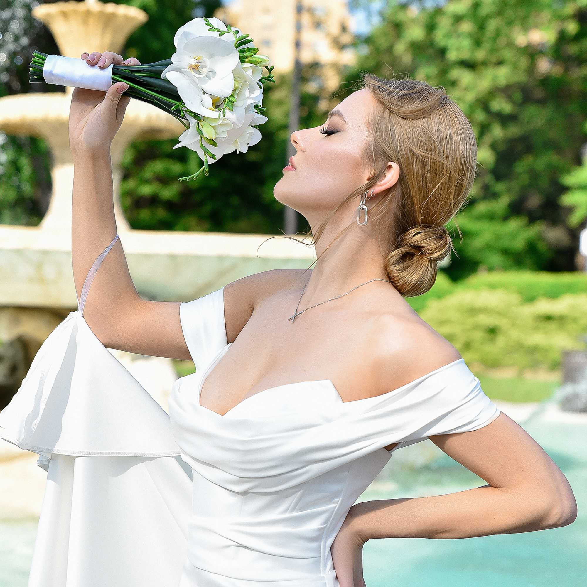 Bride holding a white orchid bouquet outdoors
