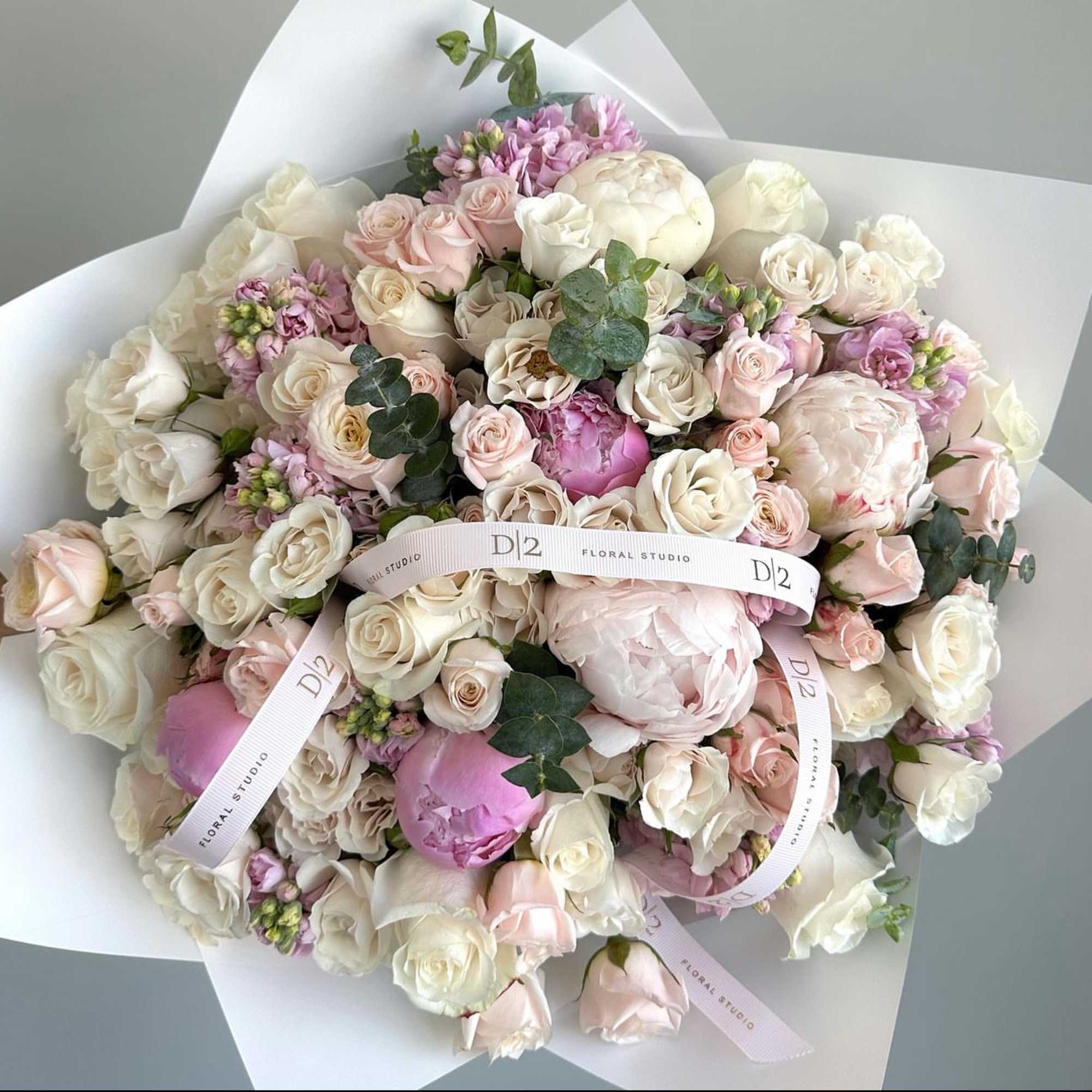 Bouquet of blush and white roses with peonies wrapped in white paper