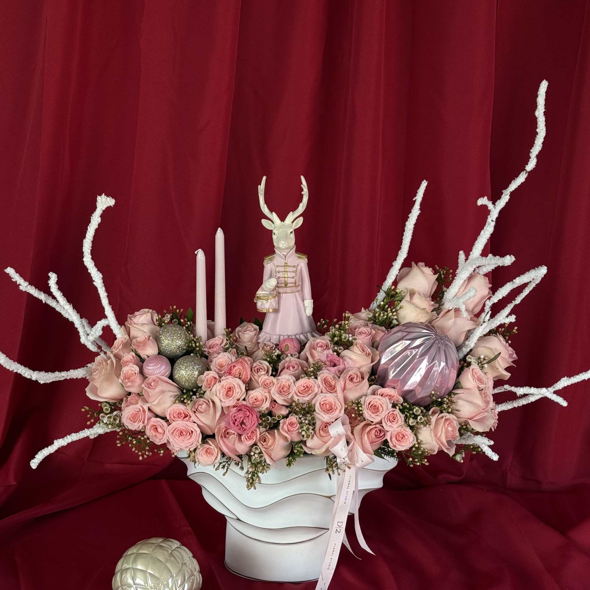 Pink rose arrangement in a white vase with candles and decorative ornaments