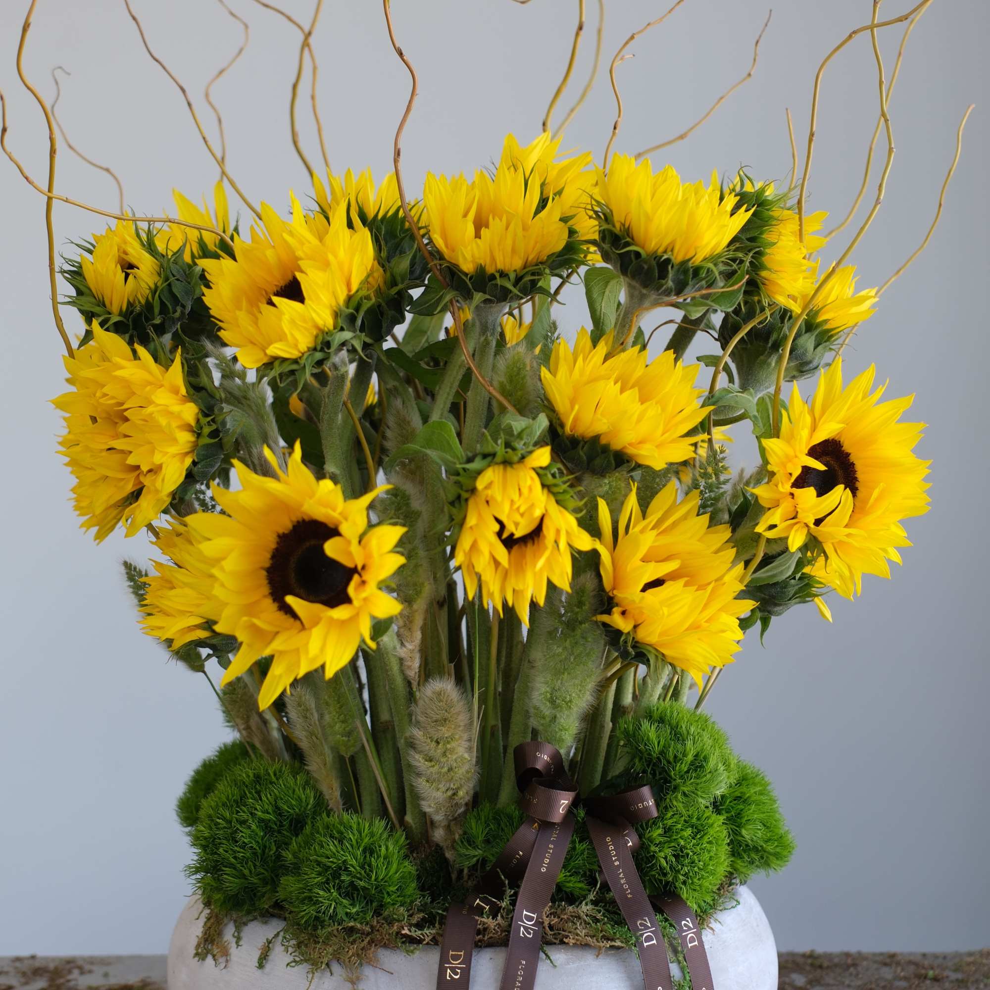 Arrangement of yellow sunflowers in a white bowl vase