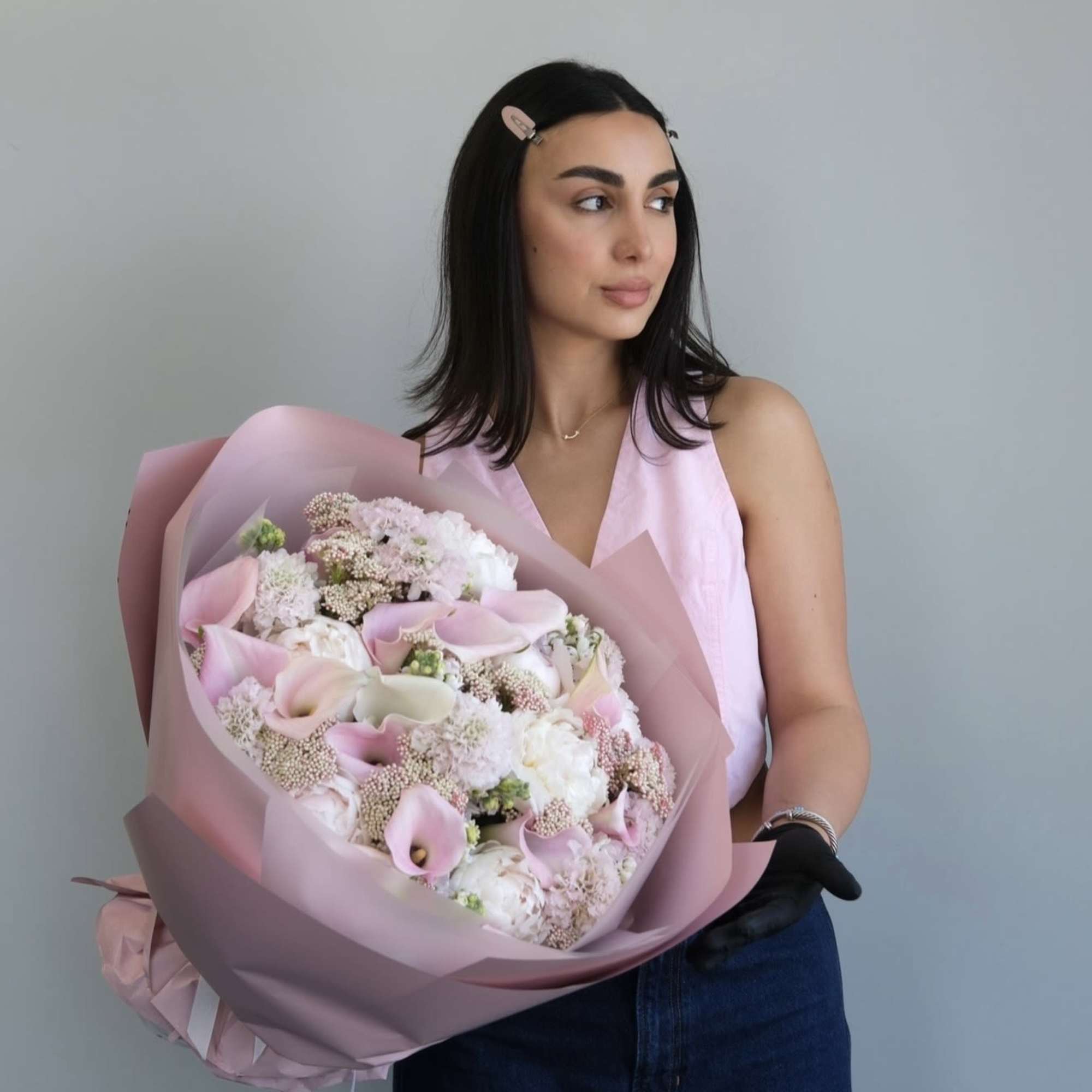 Woman holding a large bouquet of pale pink and white flowers wrapped in pink paper