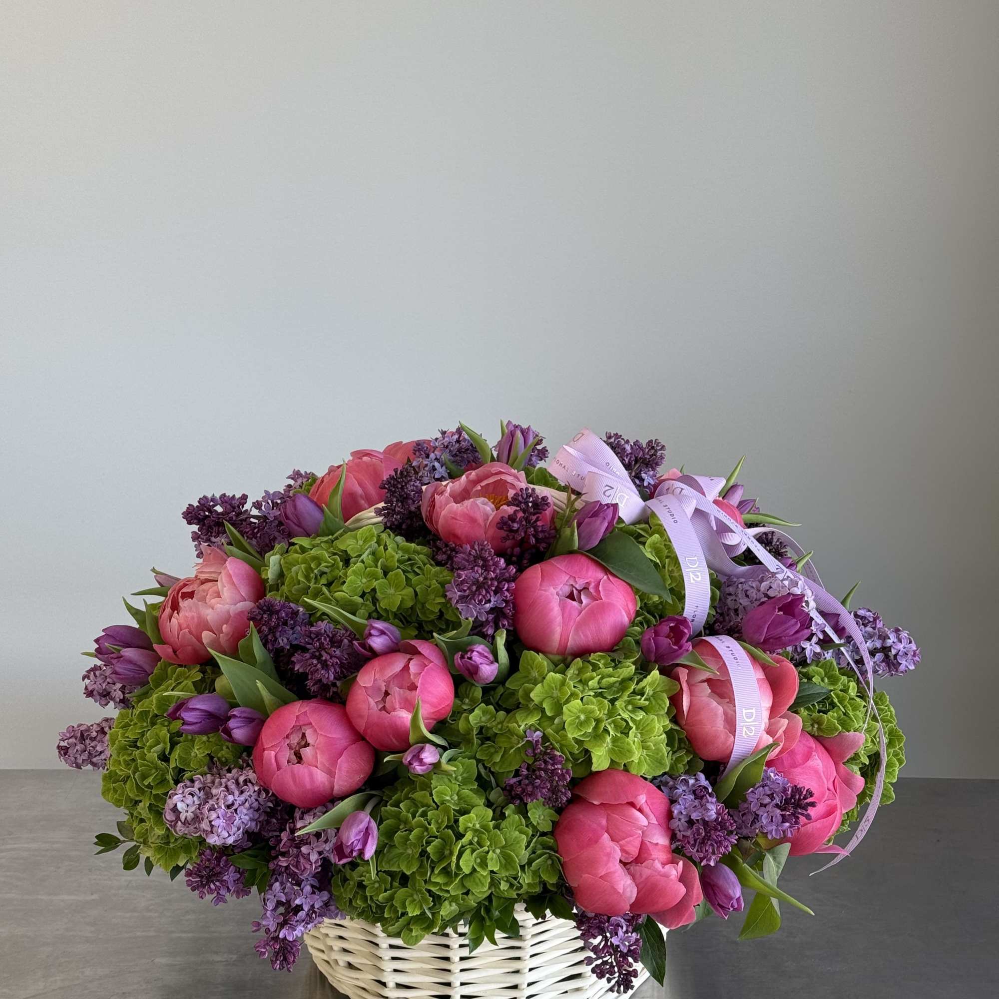 Pink peonies and purple lilacs in a white basket