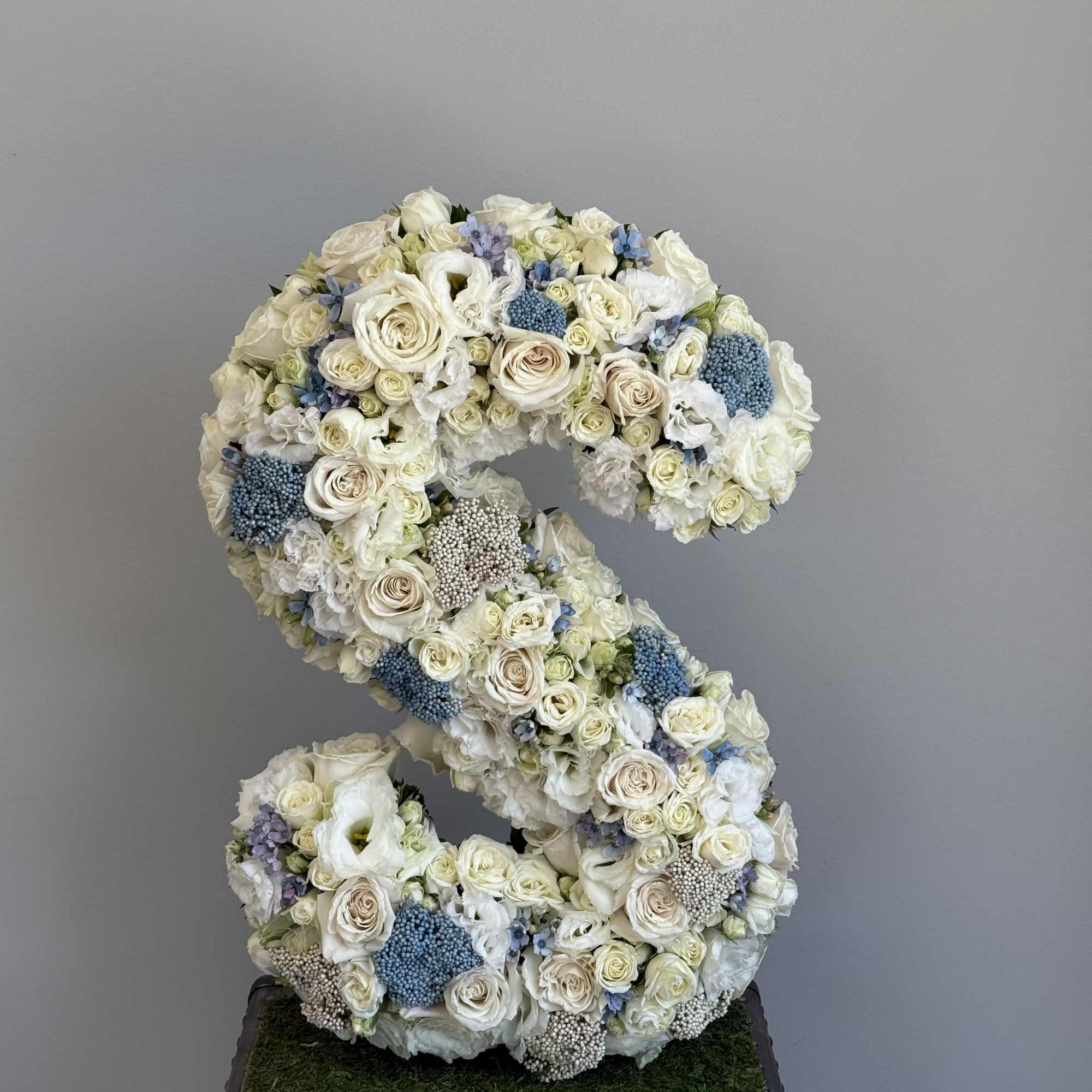 Large floral letter S made of white and pale blue flowers