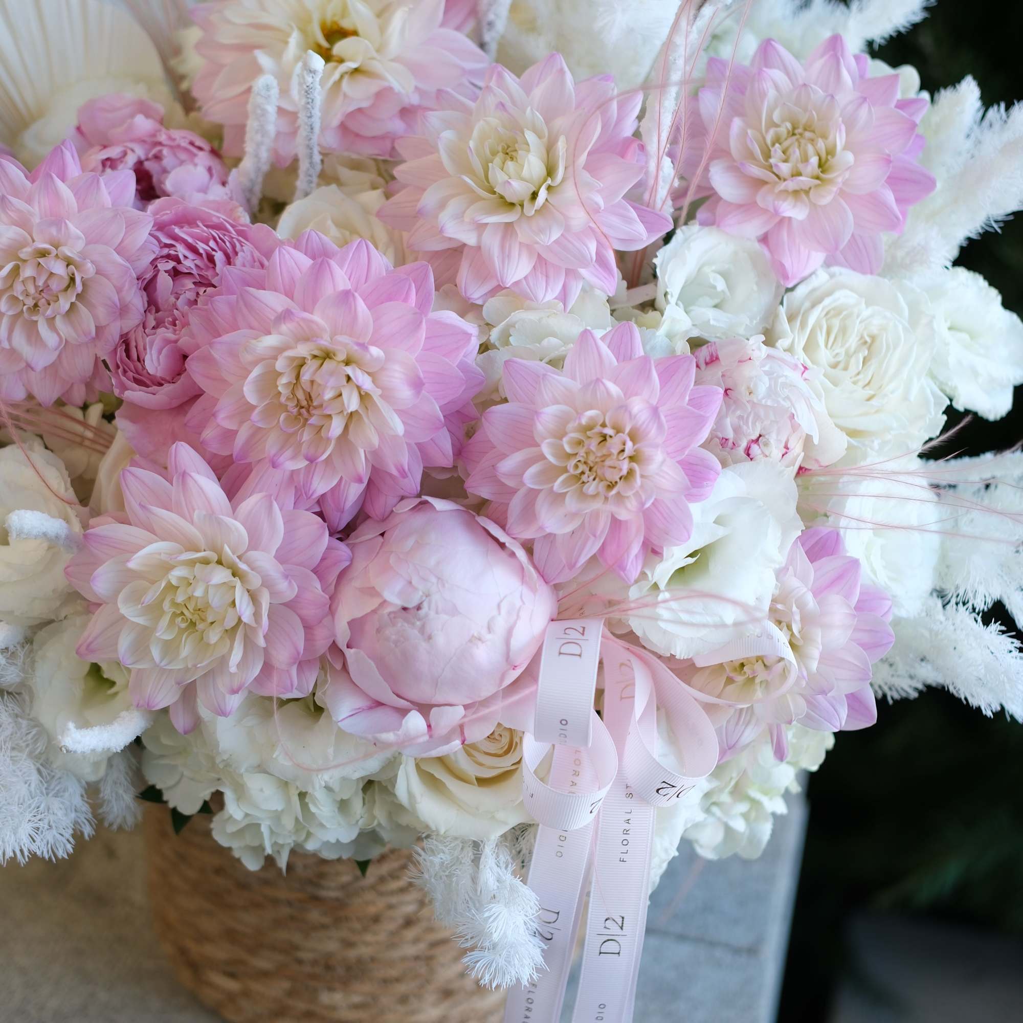 Pink and white bouquet with large dahlias in a woven basket